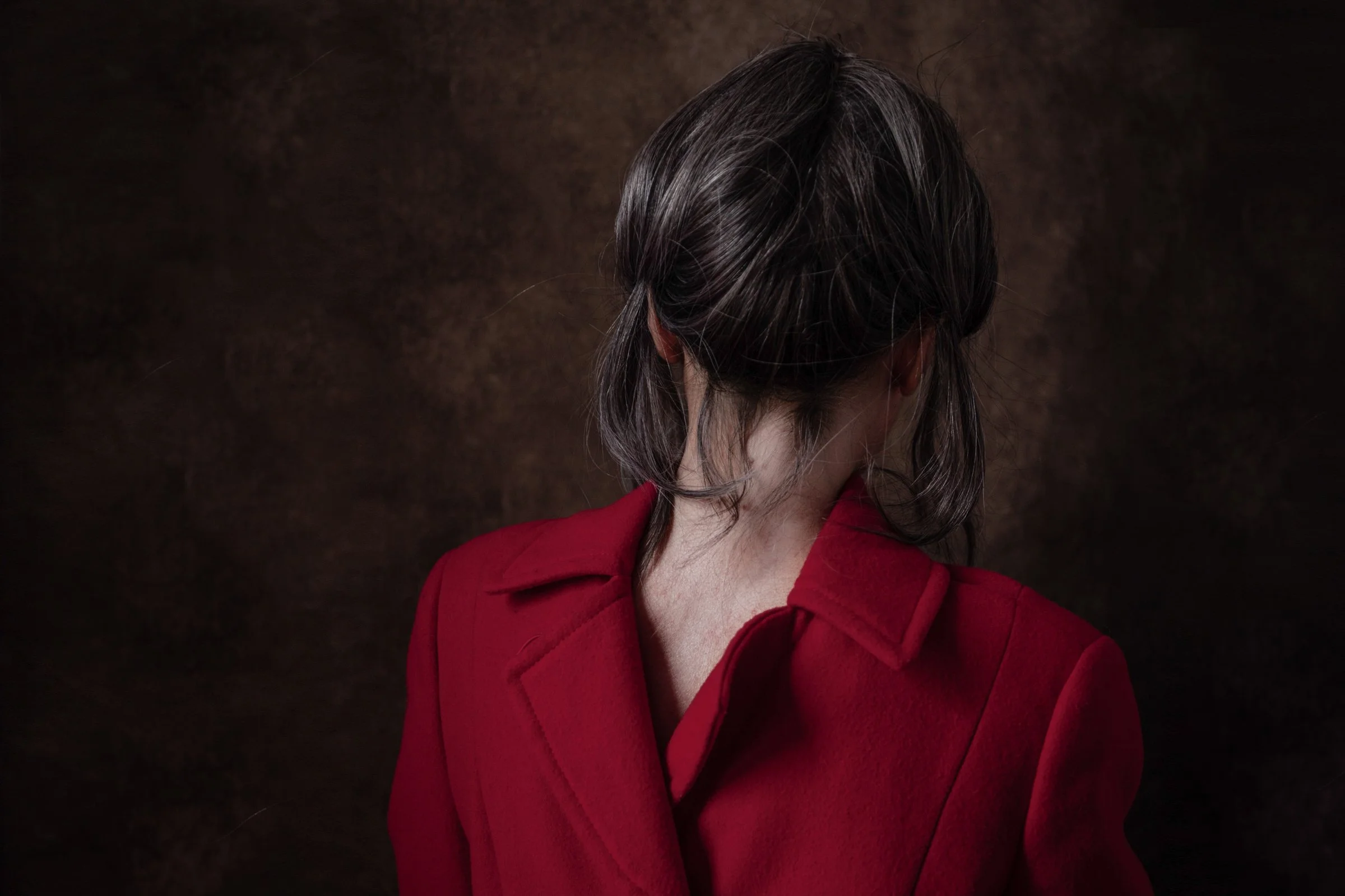Behind Your Head (The Dianara, 2022), Susanna Fiona Murray. A figure in a red coat photographed from behind, the garment worn backwards.
