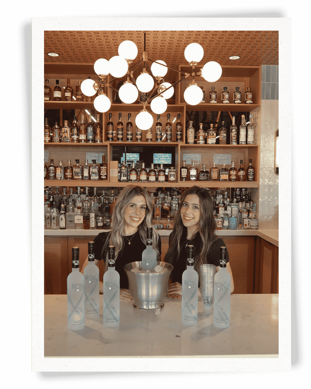 Two EPI Promotions brand ambassadors in black uniforms promoting Roxx Vodka at an upscale on-premise bar activation, representing polished beverage brand ambassador staffing by a national experiential marketing agency.
