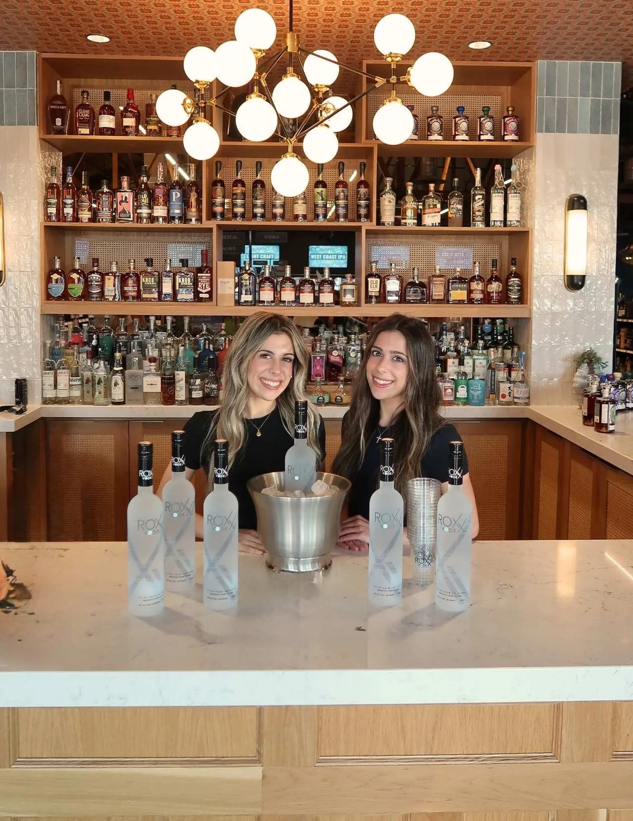 Two EPI Promotions brand ambassadors in black uniforms promoting Roxx Vodka at an upscale on-premise bar activation, representing polished beverage brand ambassador staffing by a national experiential marketing agency.