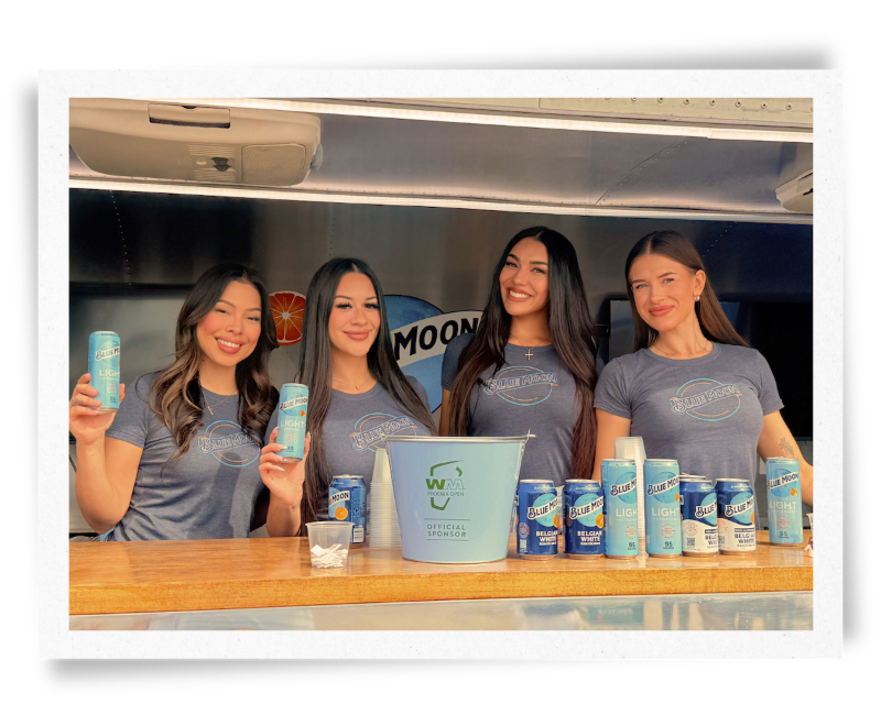 Four EPI Promotions Brand Ambassadors in Blue Moon branded uniforms smiling at the WM Phoenix Open, representing a team that pays reliably, prepares thoroughly, and supports Brand Ambassadors at every event.