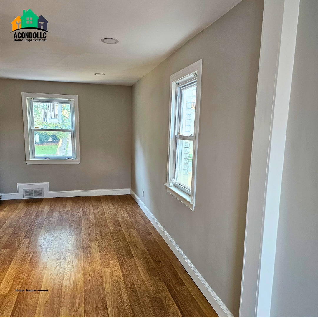 Empty room with hardwood floors, light gray walls, white trim, and two windows letting in natural light.