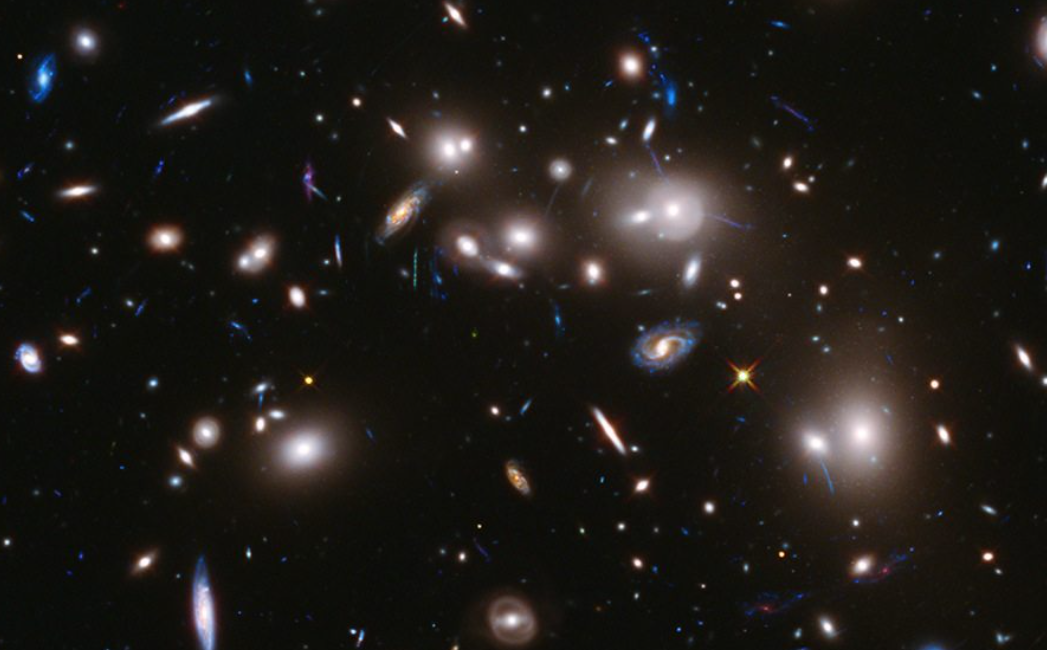 Deep space image showing numerous galaxies of various shapes and sizes against a black background.