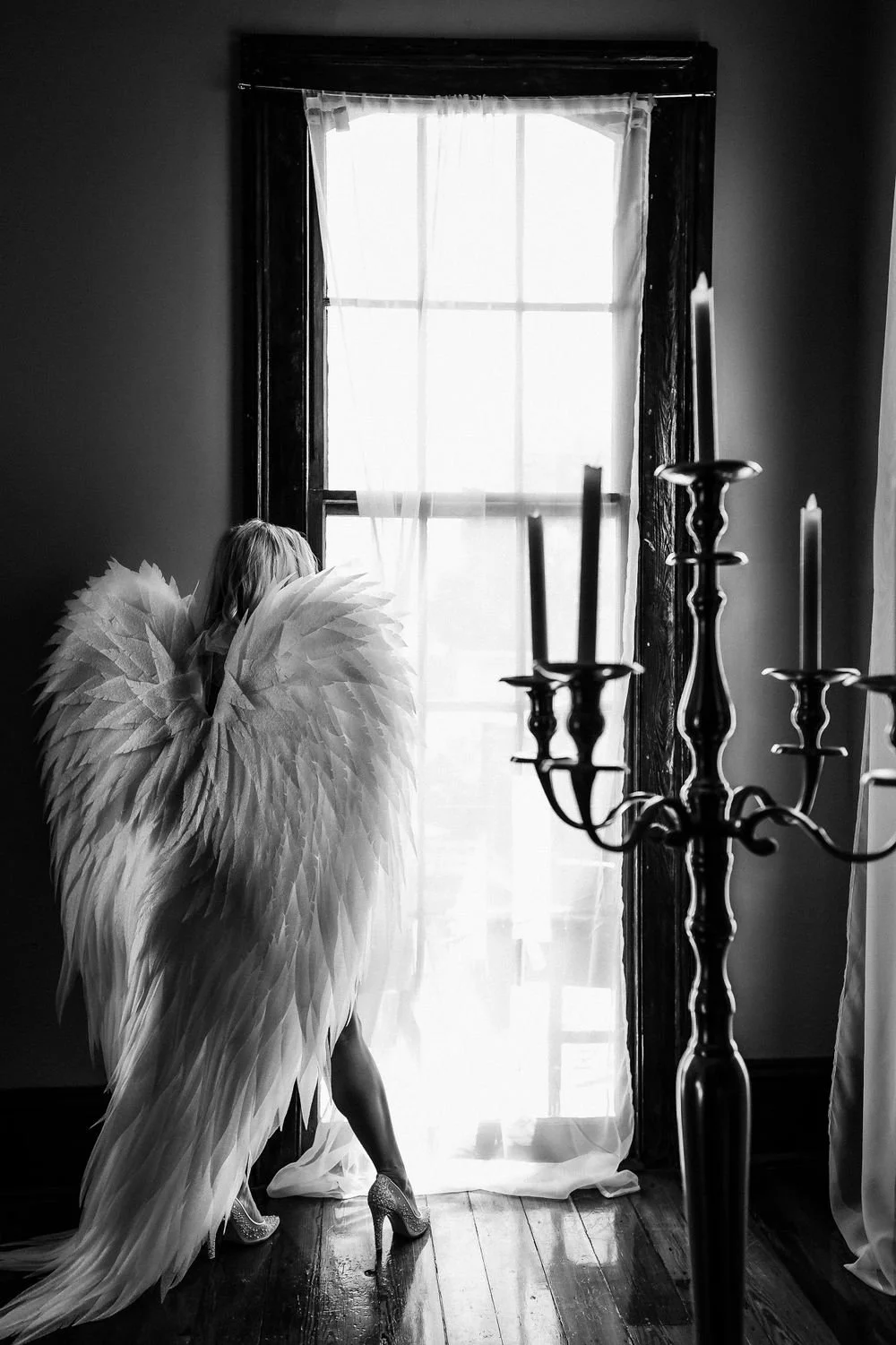 portrait of woman wearing luxurious angel wings standing in large window