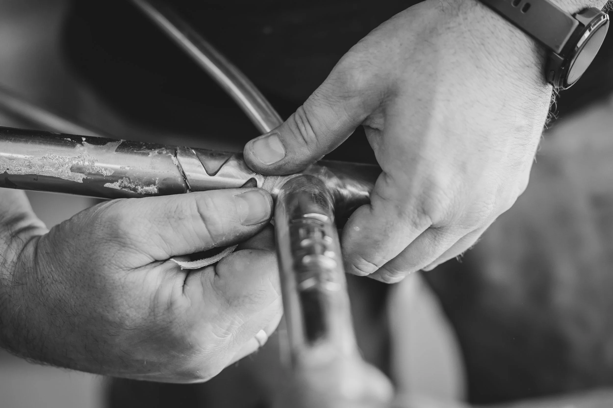 Hands sanding a silver fillet on a Columbus XCR gravelbike