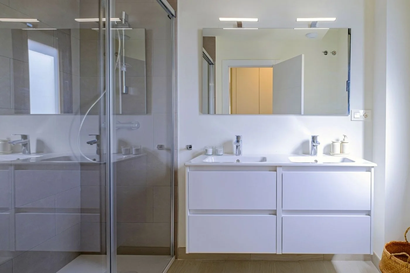 Modern bathroom with a double sink vanity, large mirror, and a walk-in shower with glass doors.