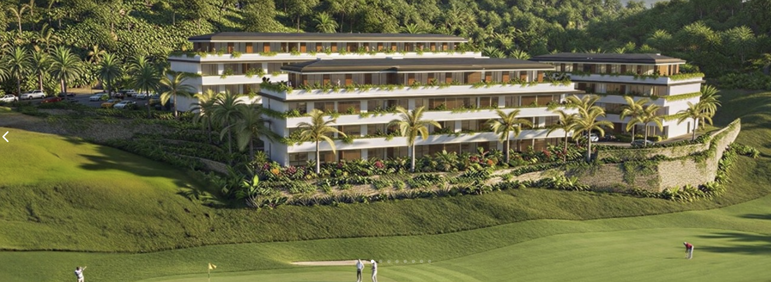Large modern white building with multiple floors, terraces with greenery, surrounded by palm trees and lush landscaping, on a hillside overlooking a golf course with people playing.