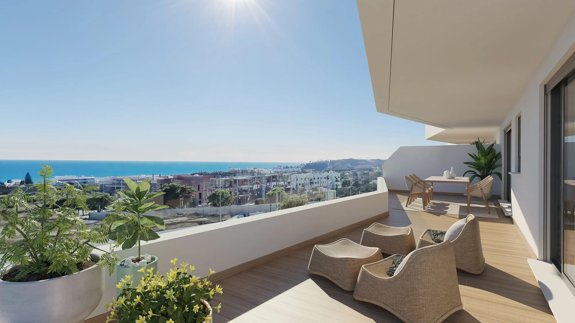 Balcony with outdoor seating, potted plants, and a view of the ocean and cityscape under a clear sky
