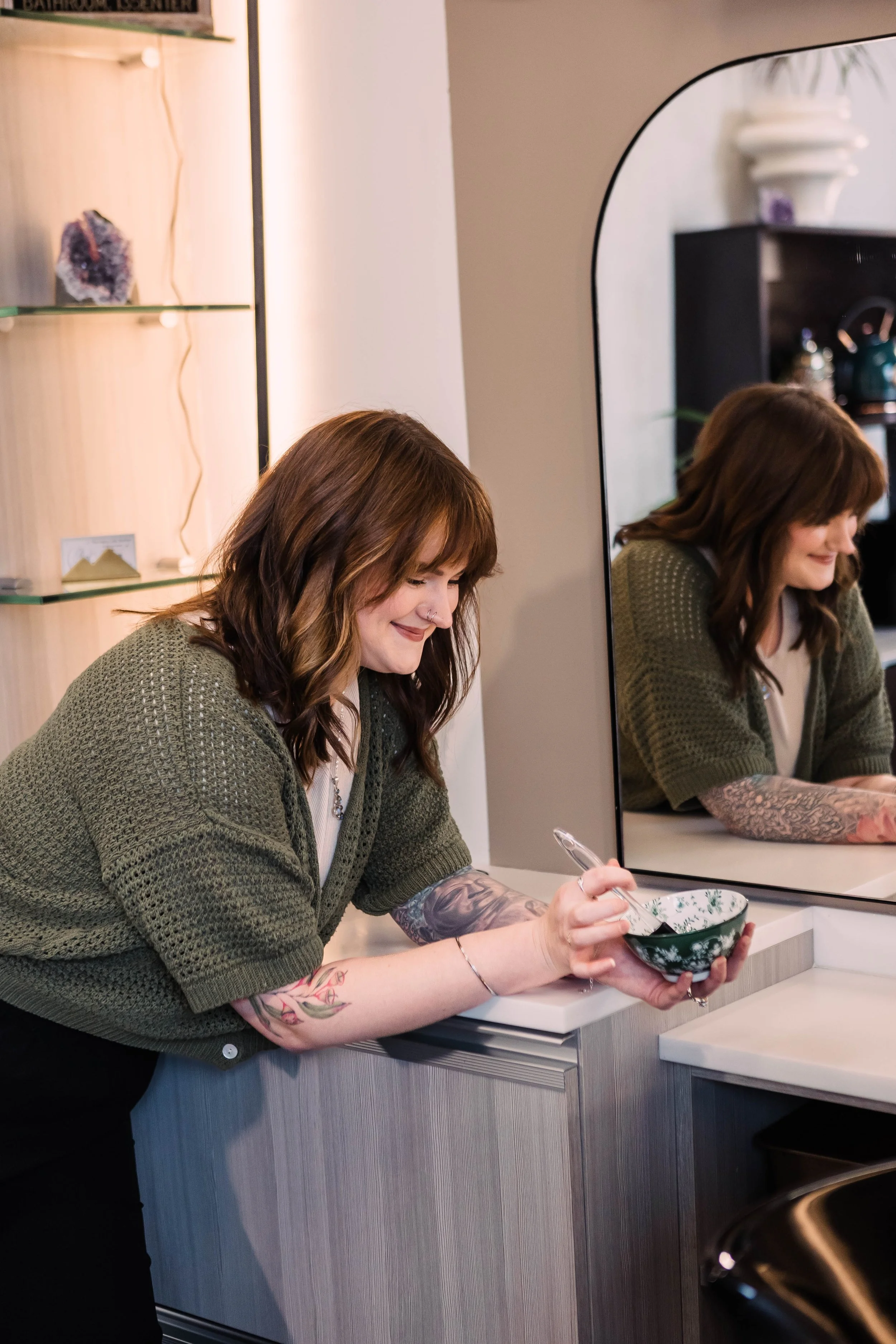 A hairstylist blow-drying a woman's hair in a salon.