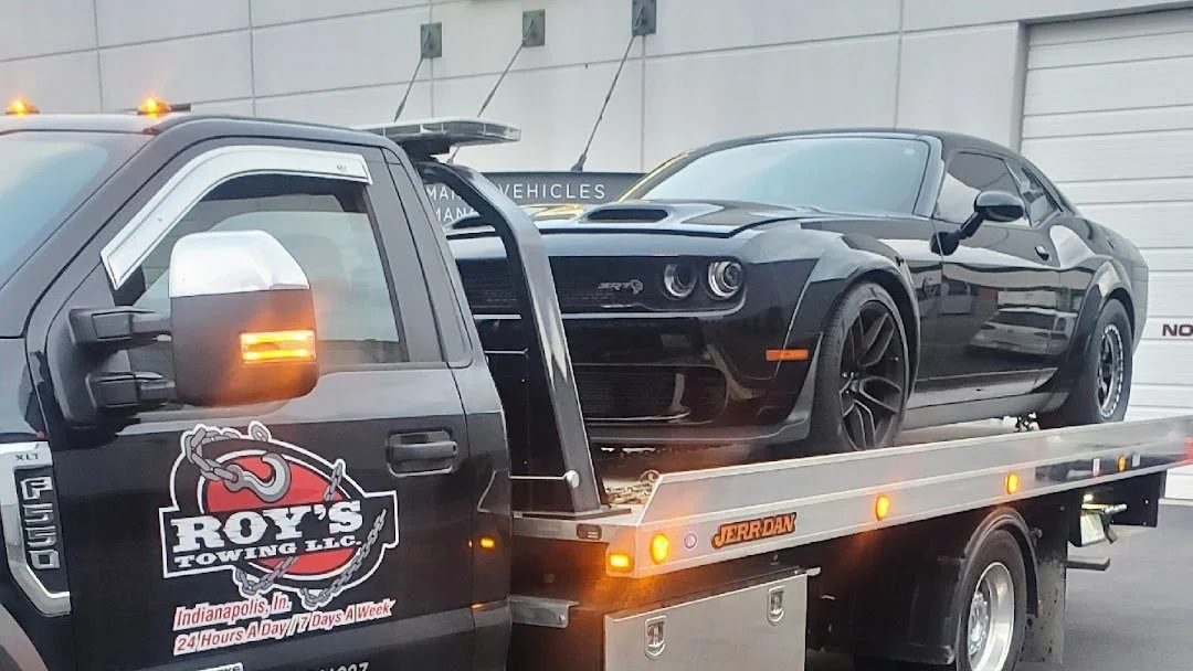 Black tow truck with a second black sports car on its flatbed.
