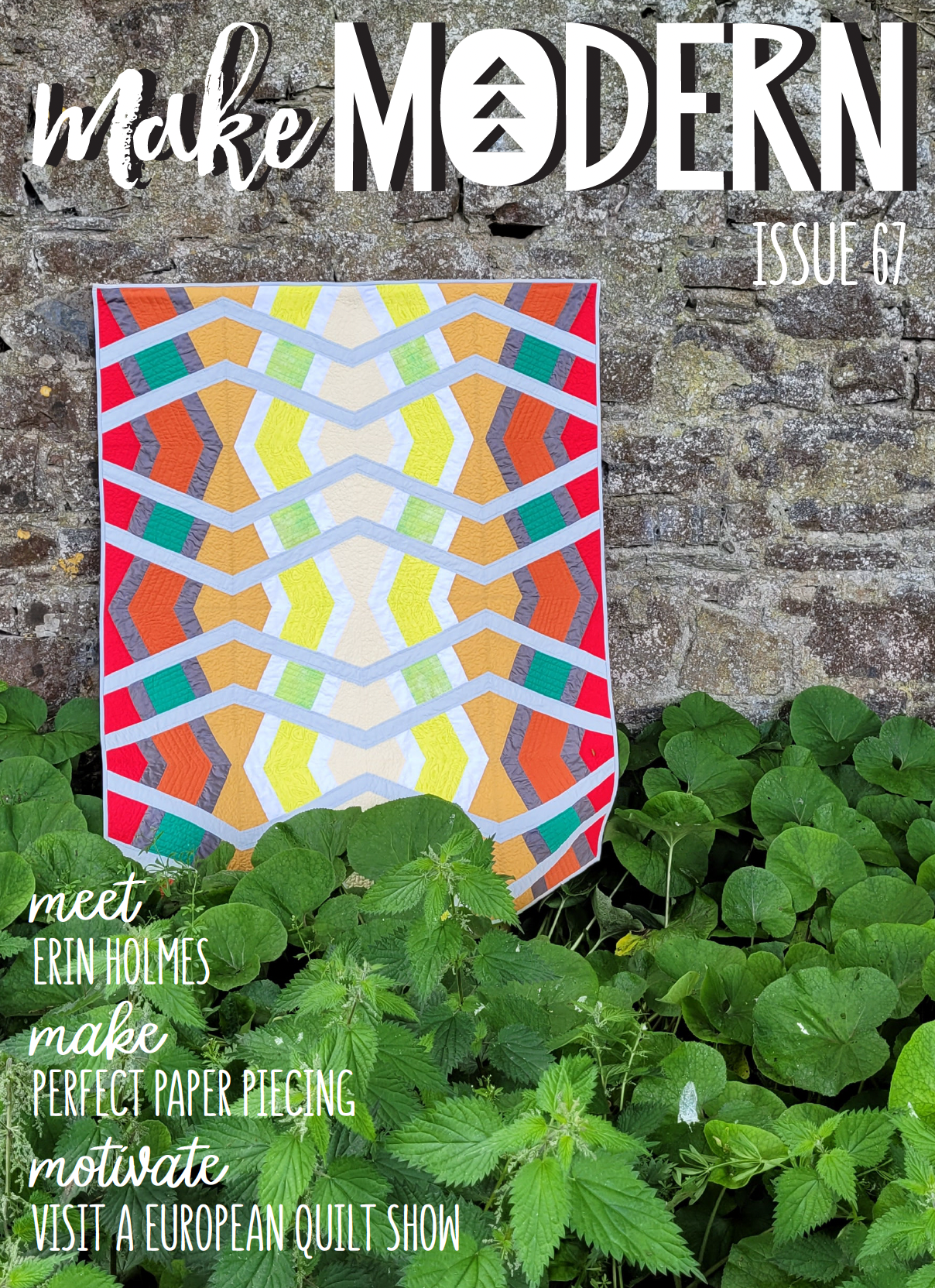 Front cover of a magazine with a linear quilt hanging in the background surrounded by plants.