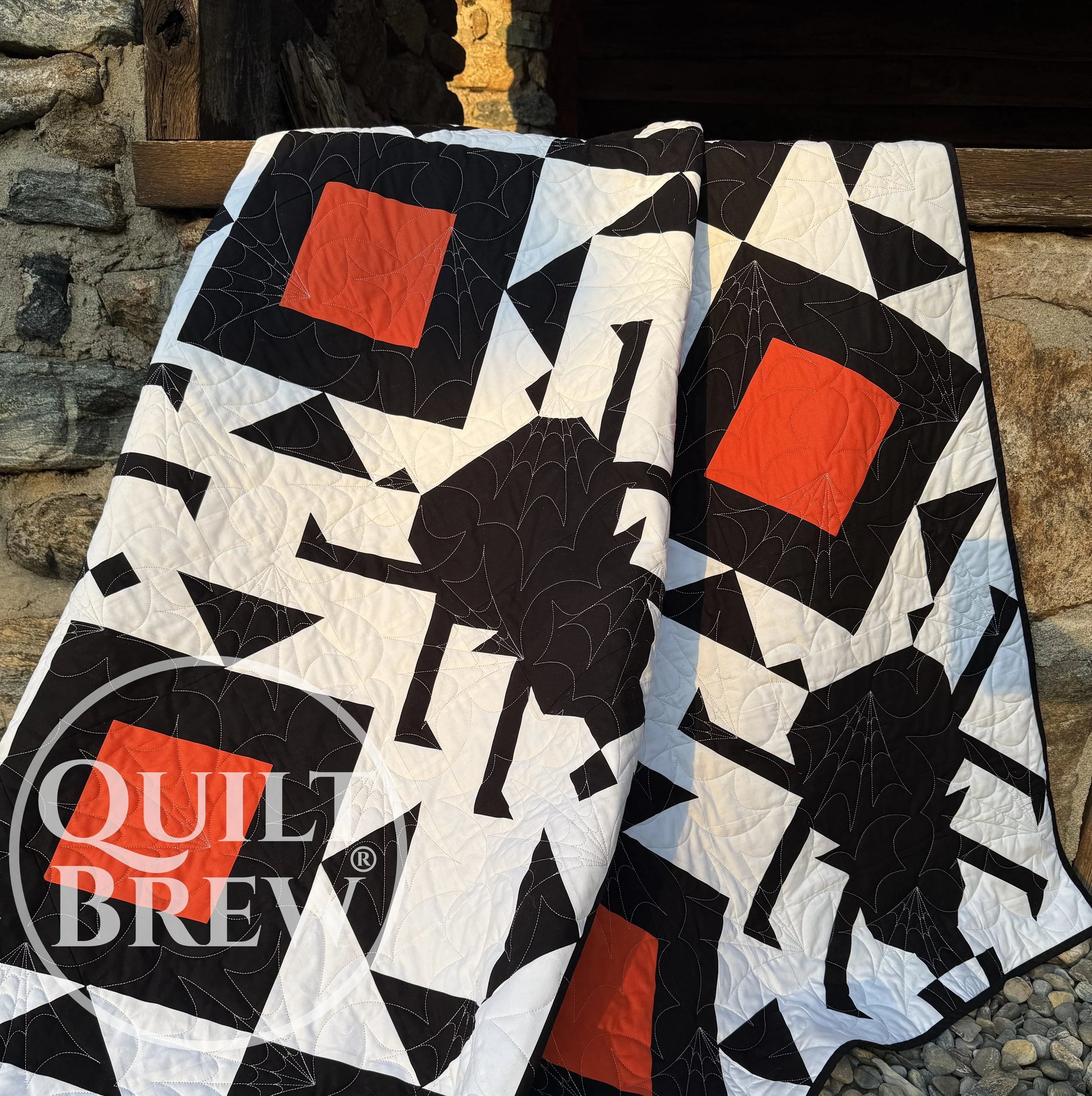 Image of a spider quilt draped over an open barn door.