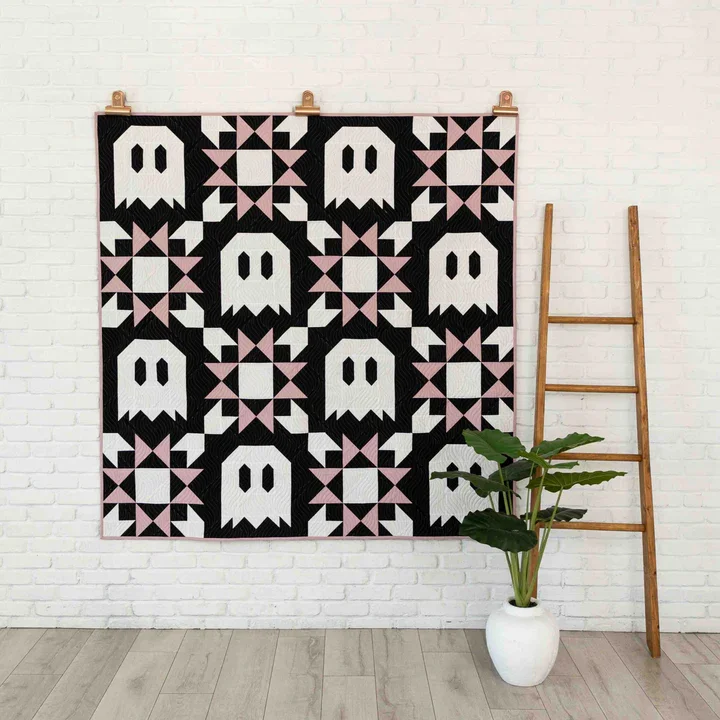 A ghost quilt is hanging on the wall.
