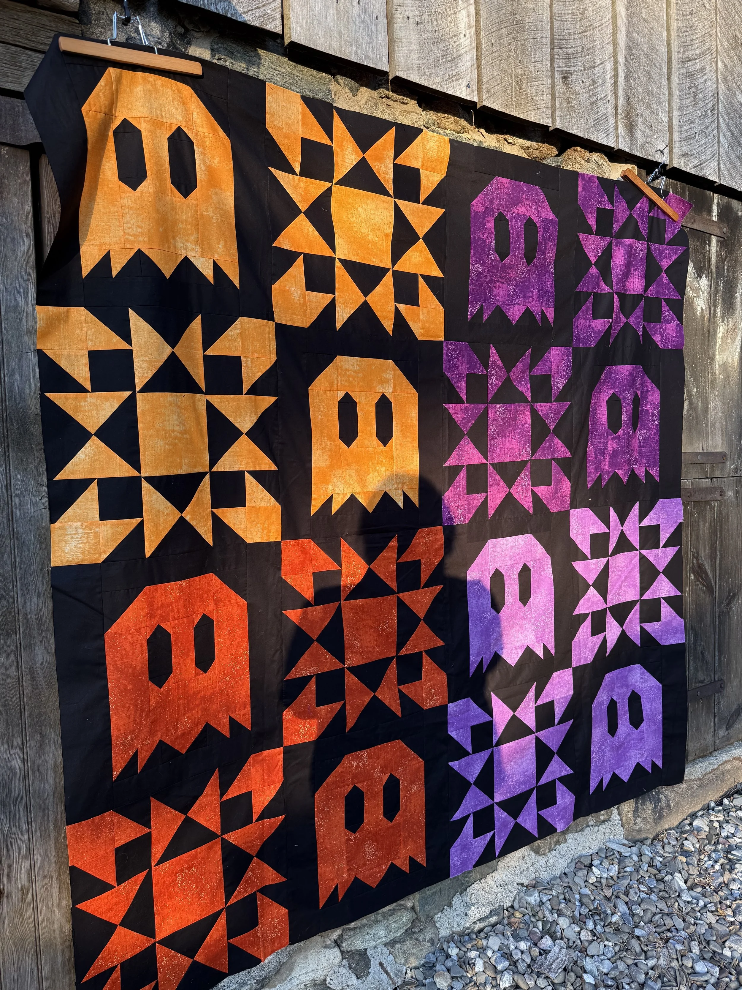A ombre ghost quilt hangs on an old barn door.