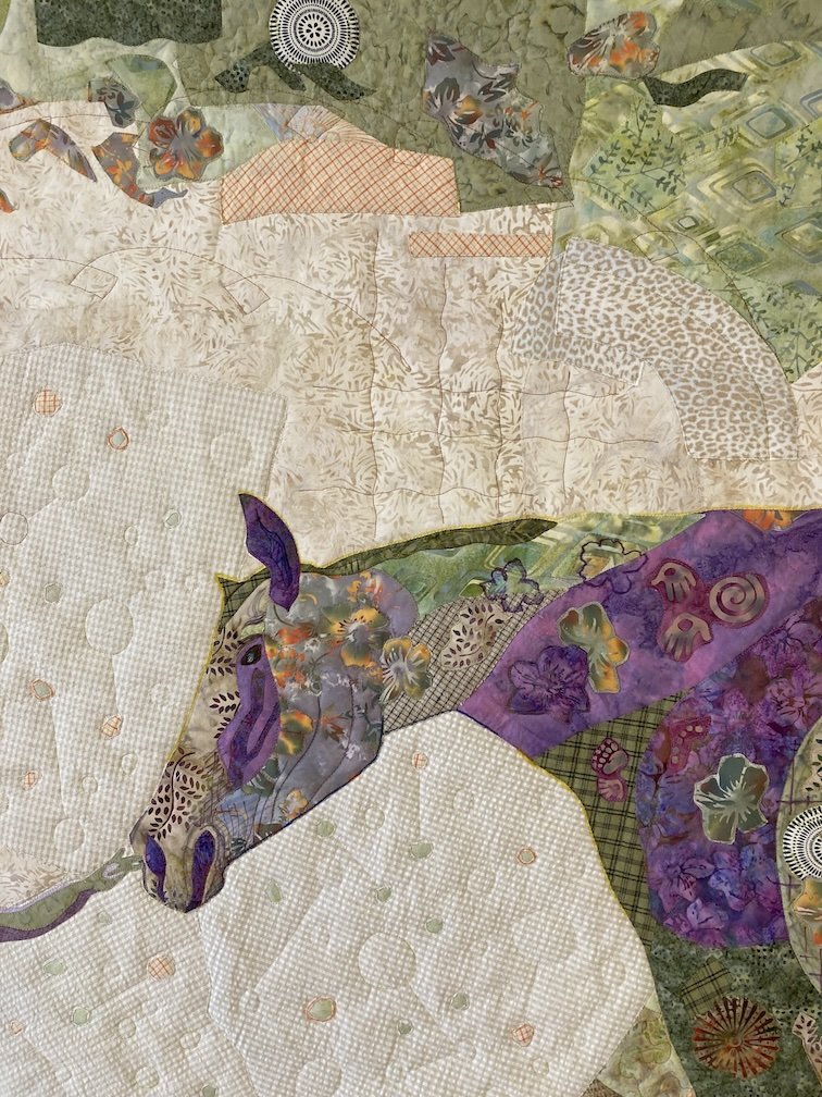 Horse is created using many purple, green,and orange fabrics. There is plaid, flower, and cave motifs used.