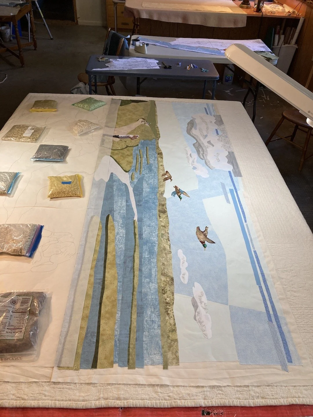 Fusing on top portion of Bolsa Chica Trails art quilt, showing sky, clouds, flying ducks, and water.