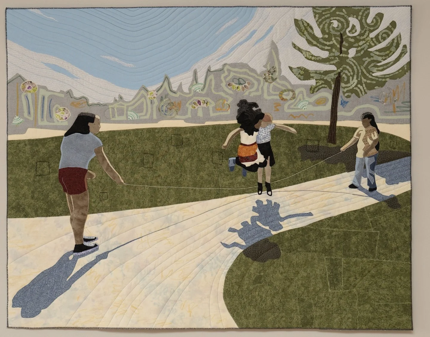We see an outdoor moment of two girls jumping rope and two older girls swinging the rope. There is a fanciful tree and backgroud.