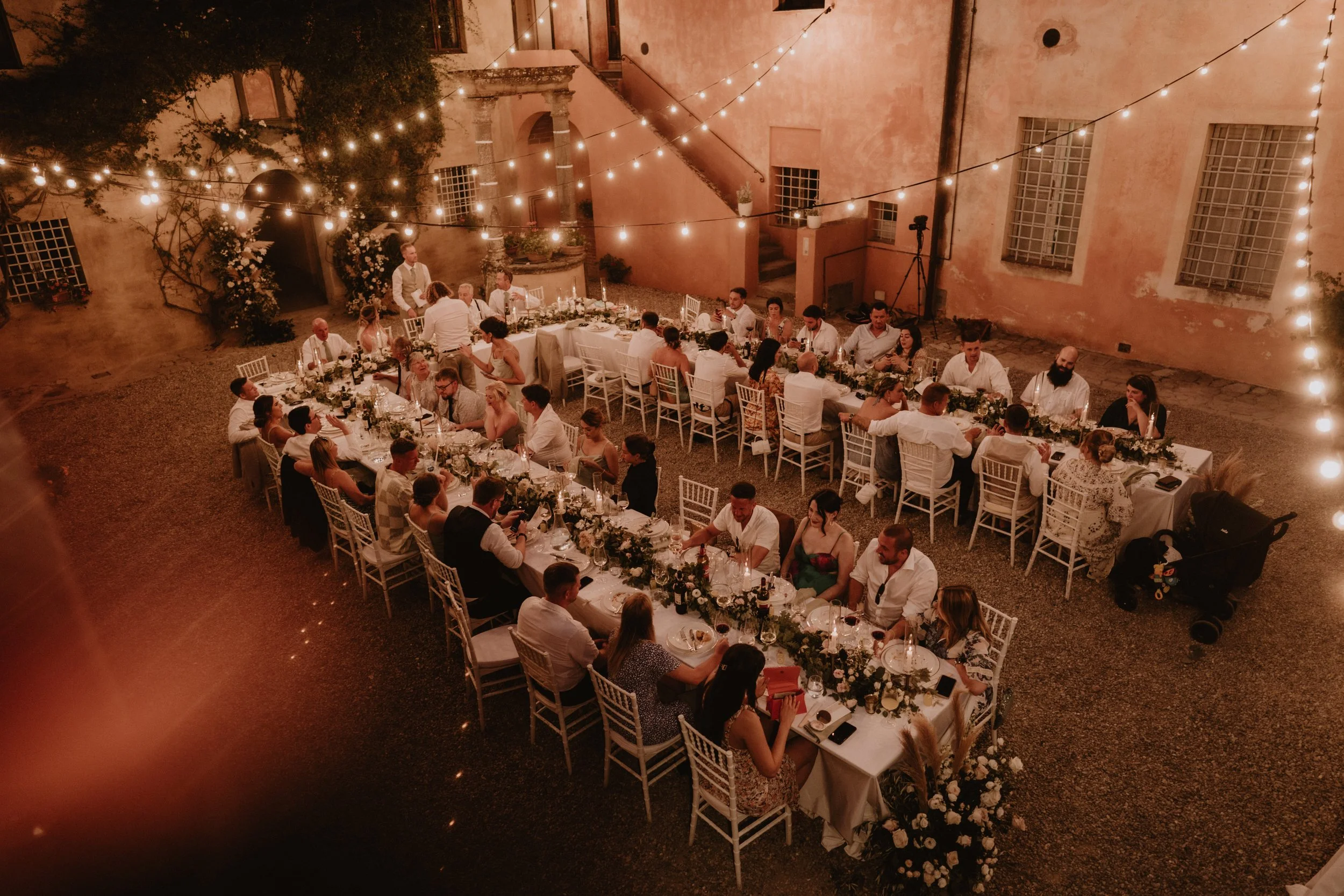 wedding guests sat down at wedding dinner in warm Tuscany light 