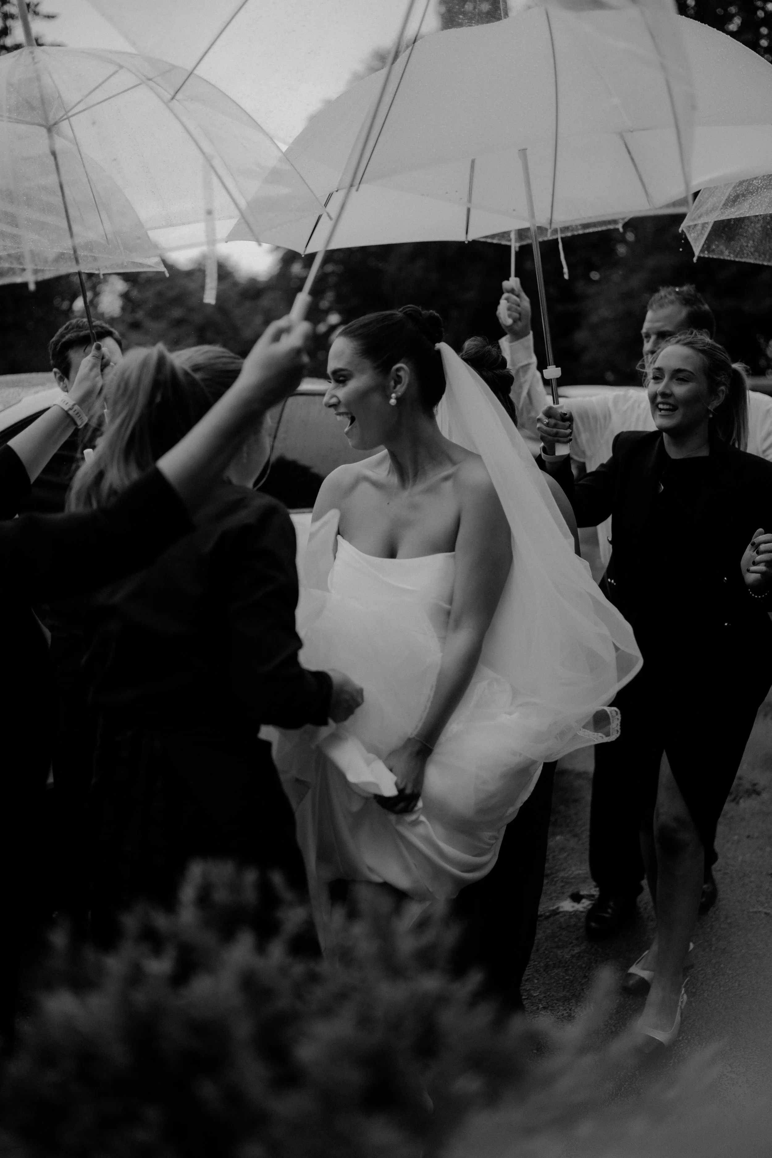 beautiful bride surrounded by wedding guests and umbrellas