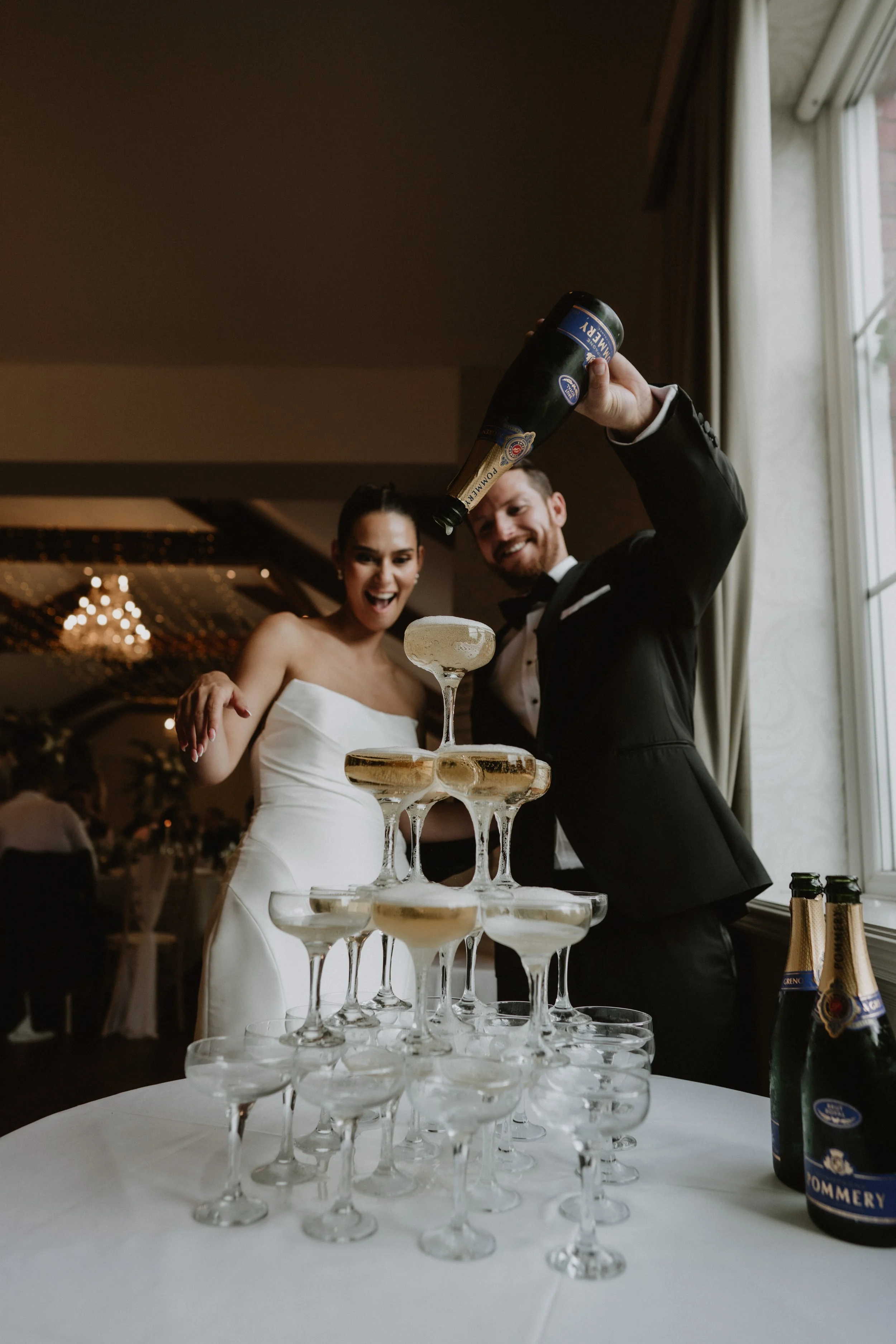Wedding couple pouring a champagne tower at Coed Y Mwstwr