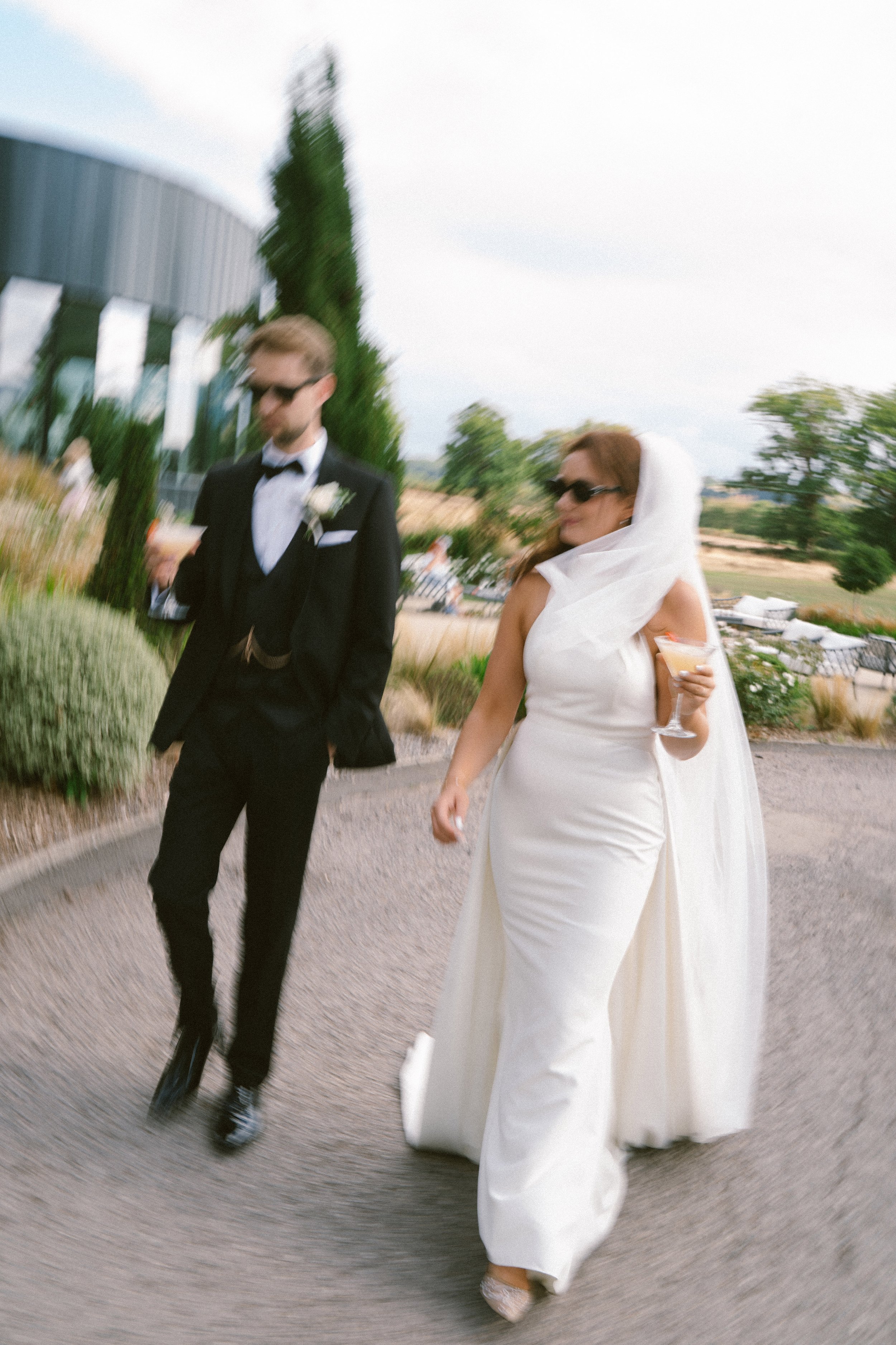 bride and groom walking with drinks wedding photography uk