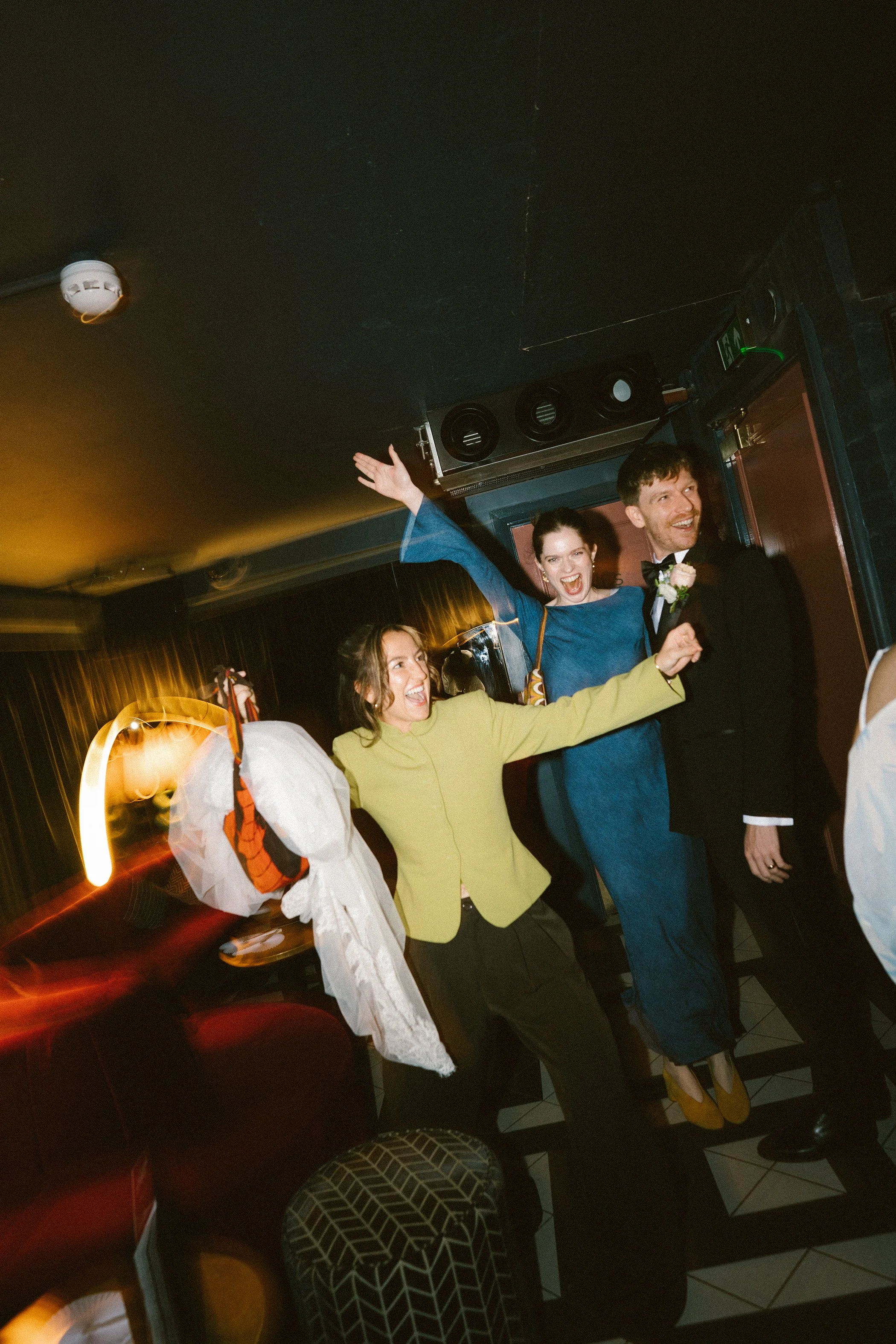 People dancing and celebrating at a party or event in a dimly lit indoor space.