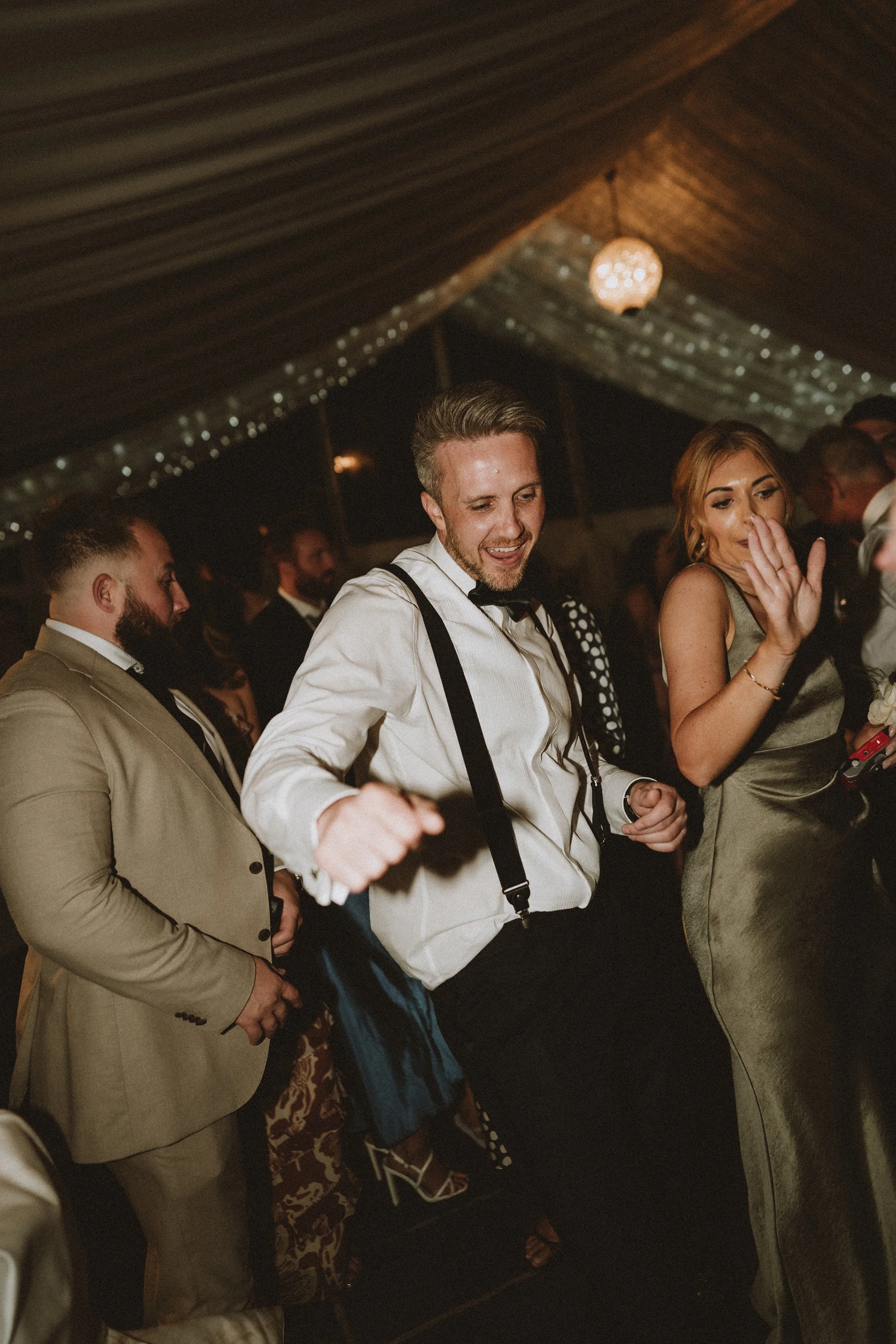 People dancing and enjoying at an indoor celebration or party under a decorated ceiling.