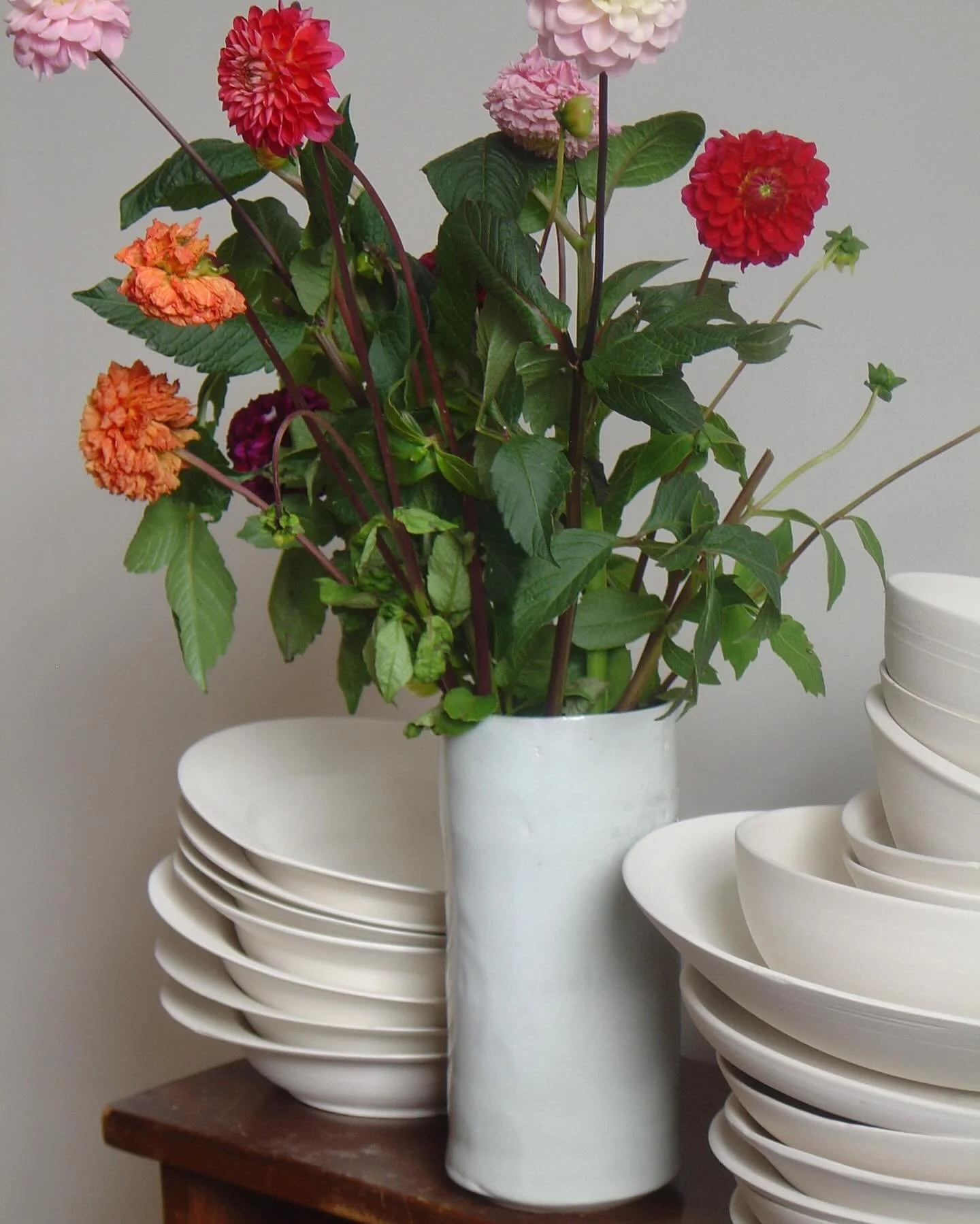 Dahlias among unfinished bisque-ware.