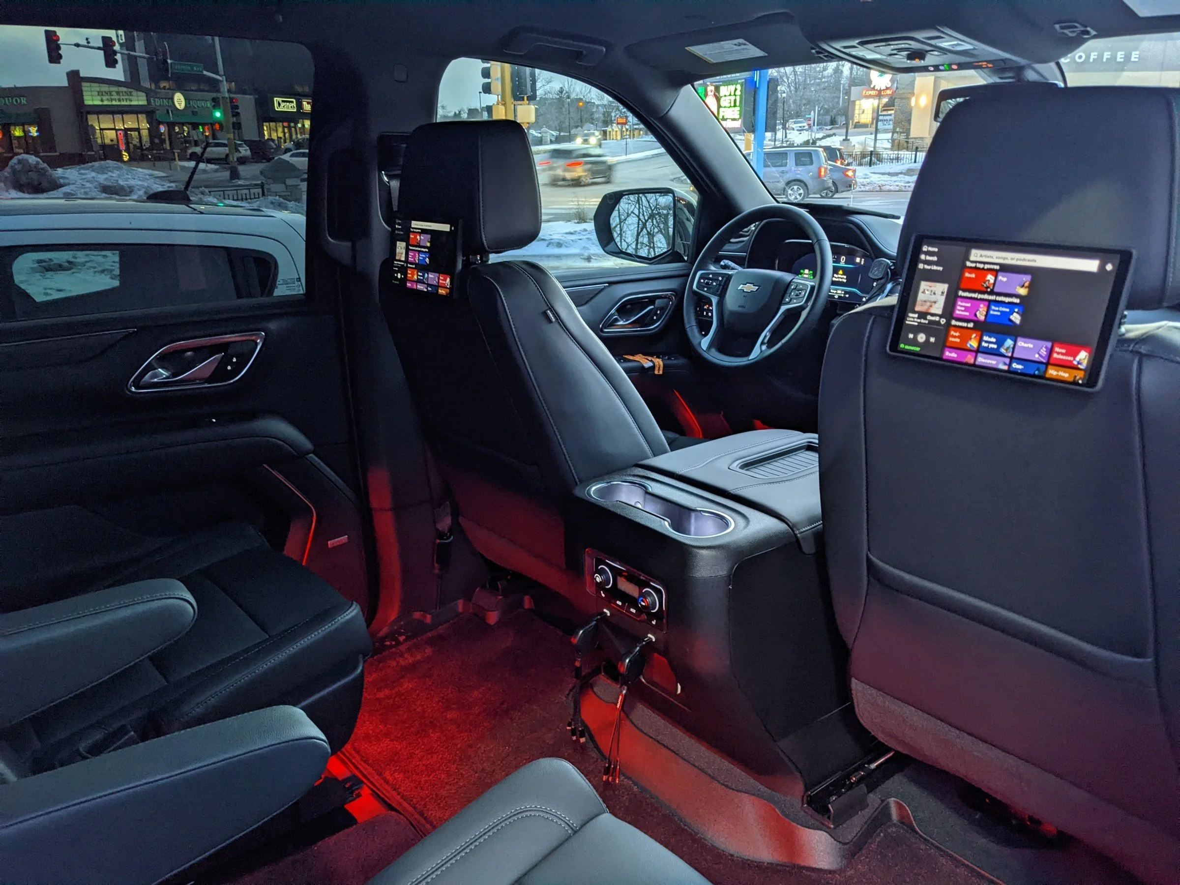 Rear seats of the For Sure Luxury Suburban with entertainment screens and ambient lighting, ready for your reservation