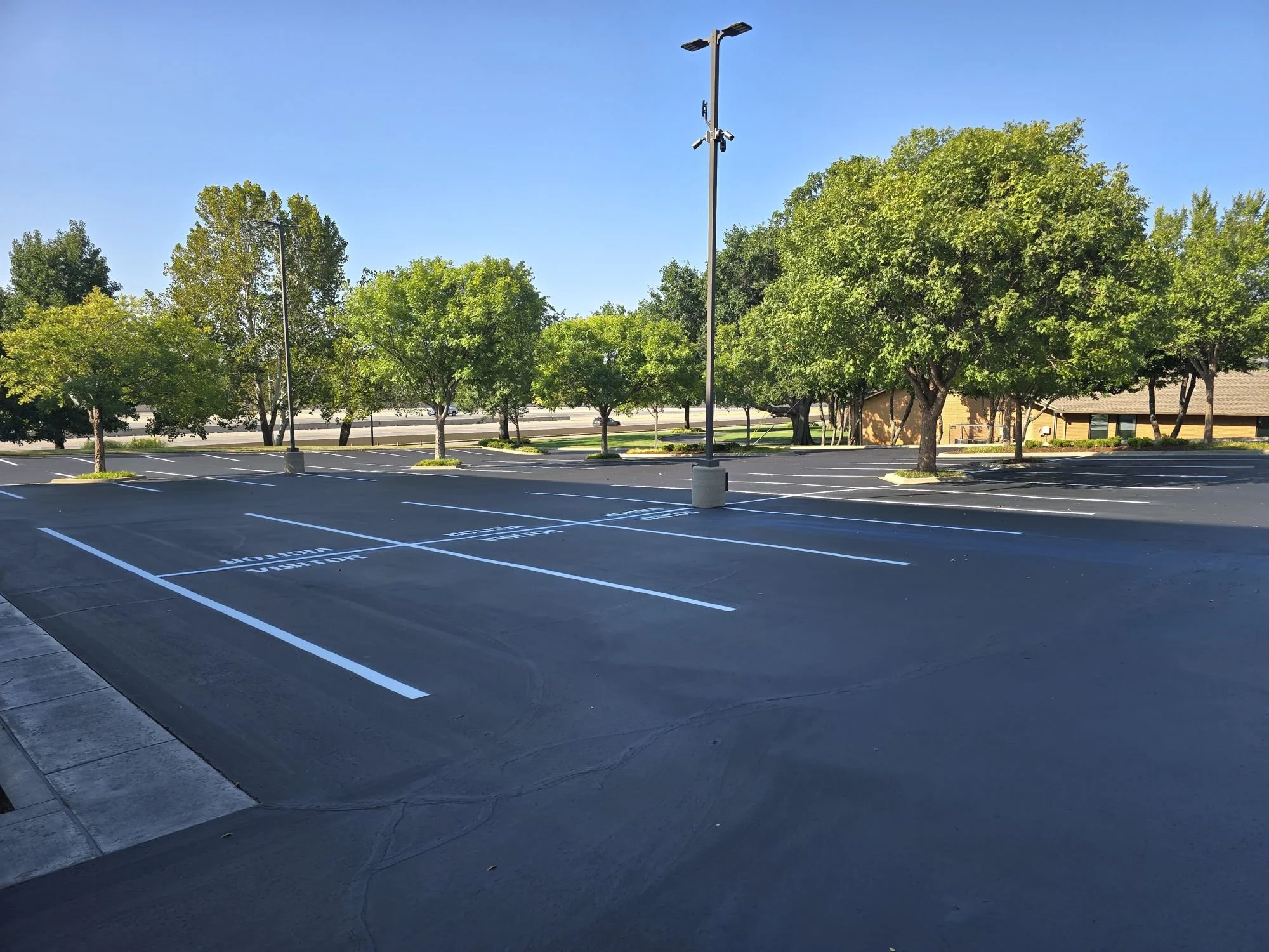 Freshly sealcoated asphalt with new striping and Visitor stencils at a MidFirst Bank corporate office in Oklahoma City