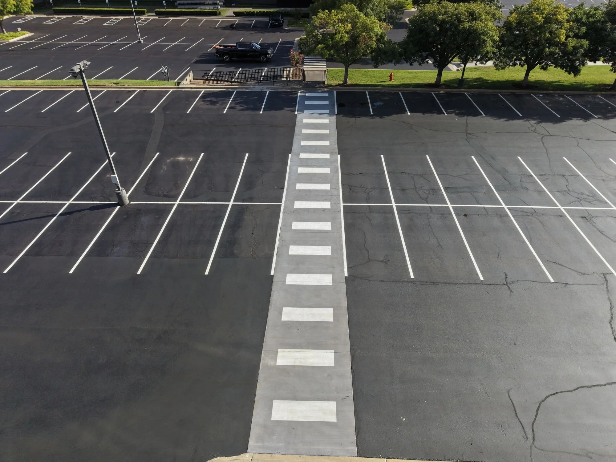 Asphalt parking lot in Oklahoma City with cracks in the pavement beside fresh striping and a crosswalk