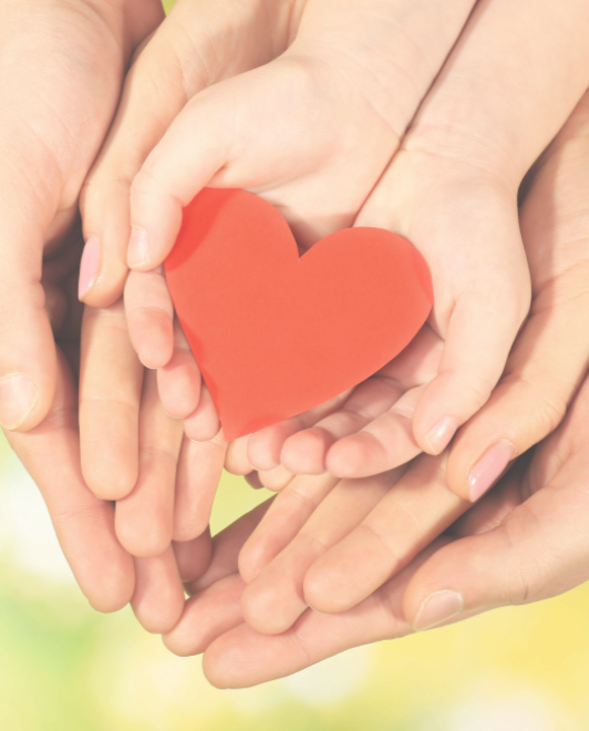 Multiple hands holding a red paper heart together.
