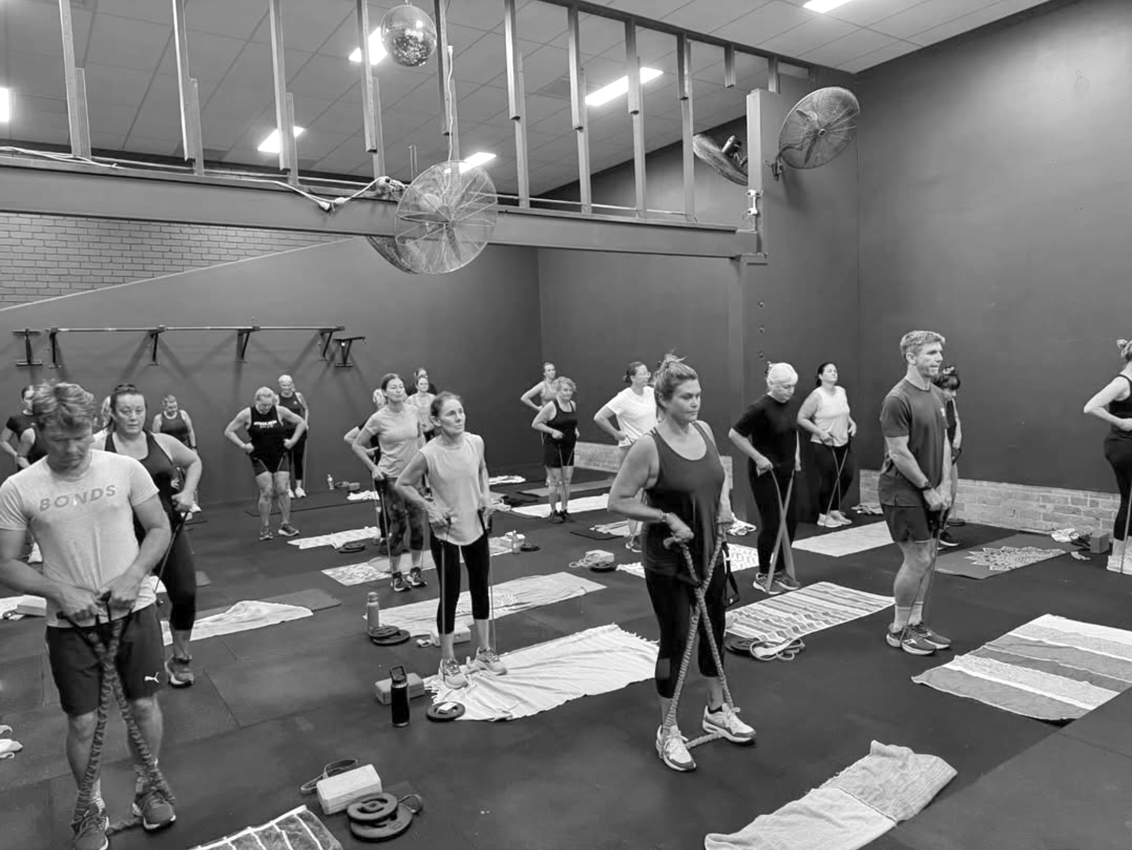 A group of people participating in a fitness class using resistance bands in a gym.