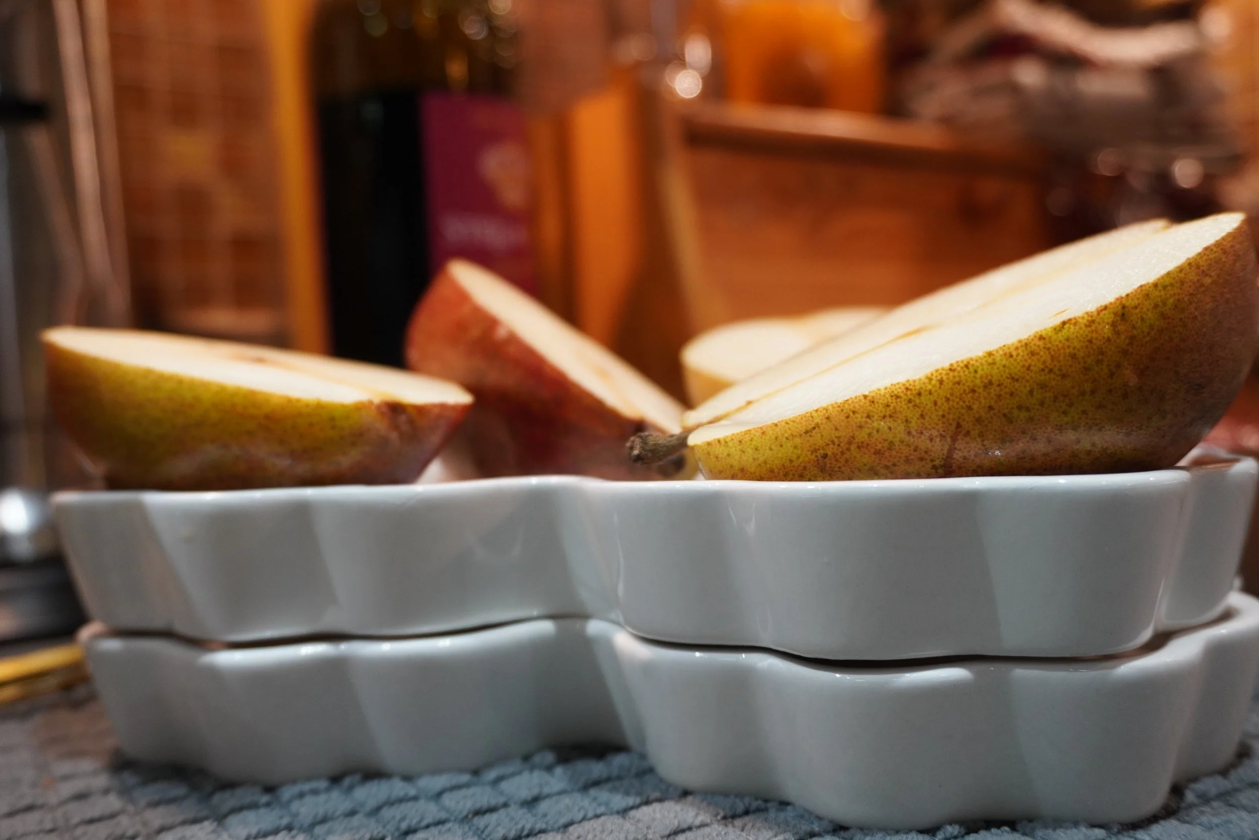 Sliced pear halves placed on stacked white ceramic dishes.