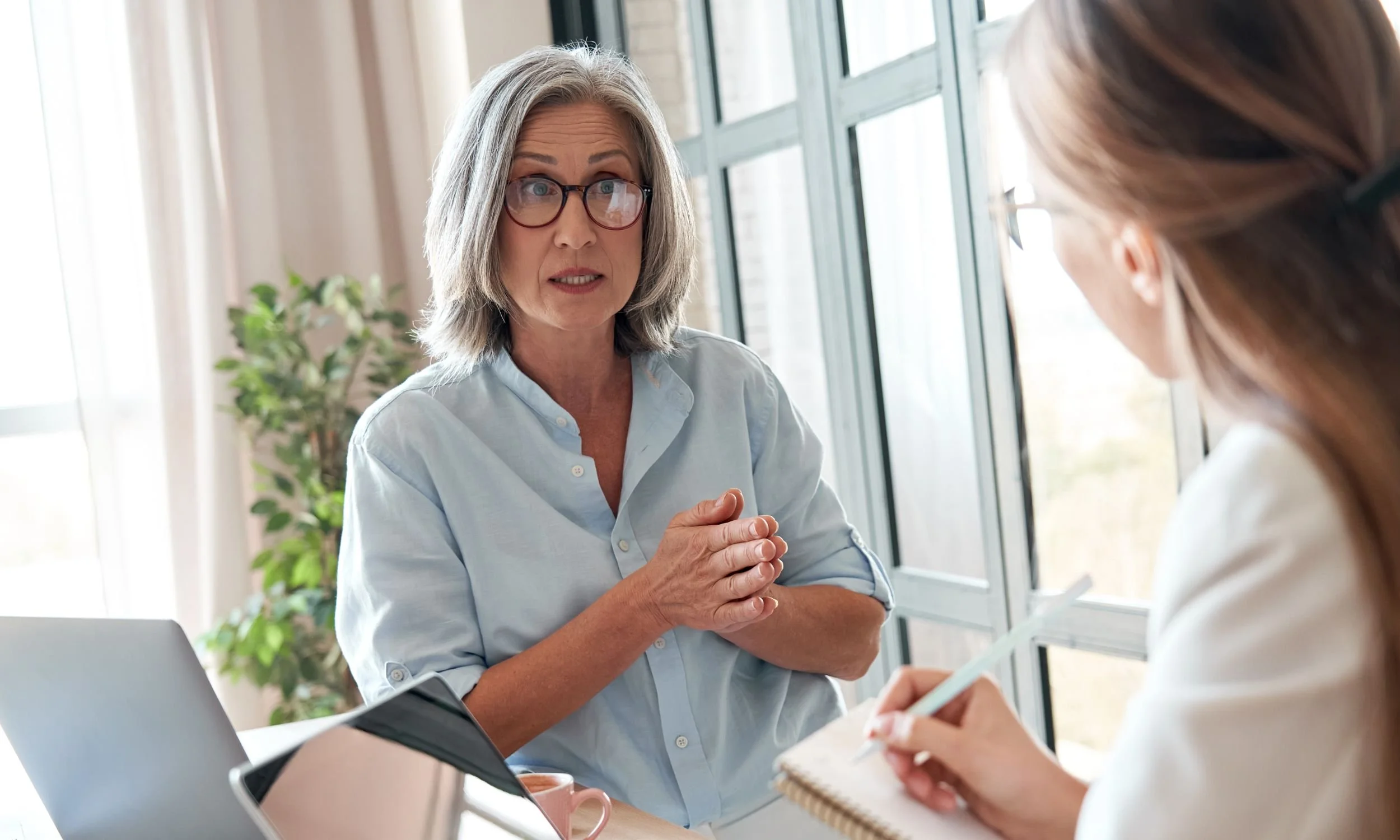 One woman with her palms together explaining something to another woman