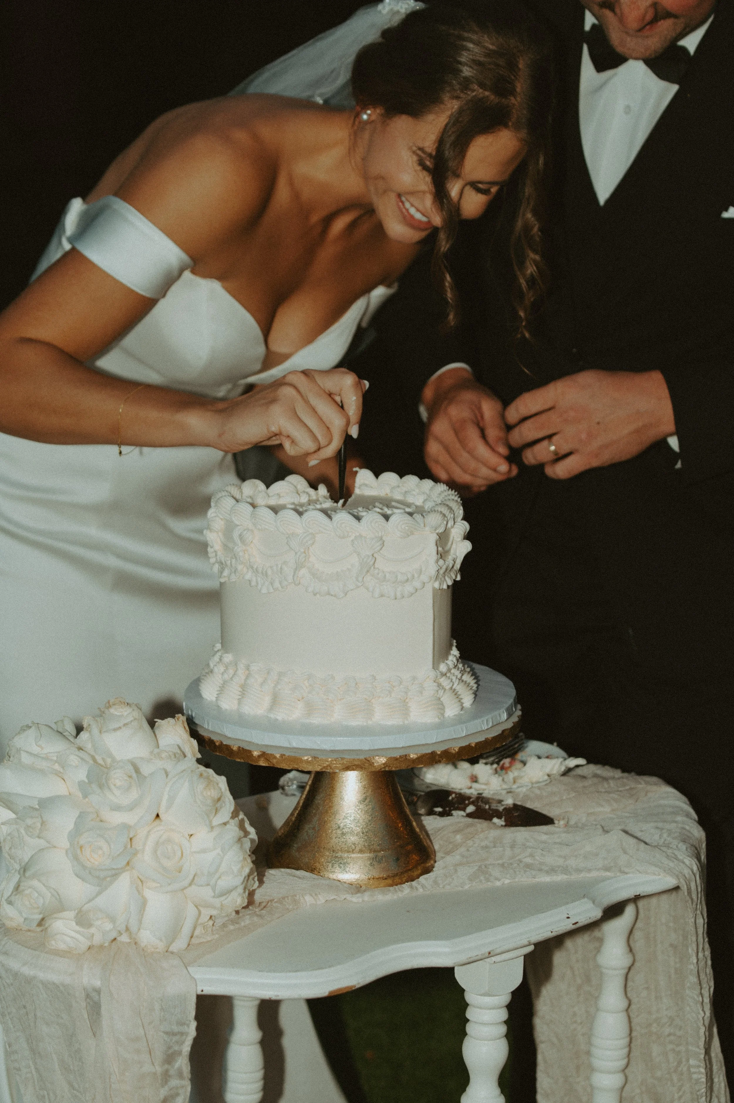 A bride and groom cutting a wedding cake together at their wedding reception.