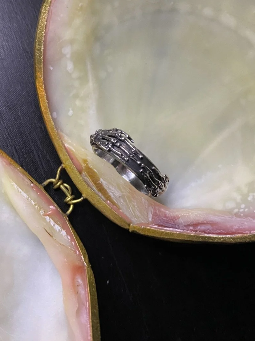 Blackened decomposing-looking skeleton ring. Debated for a while whether to interlock the fingers or have the hands reaching across and not quite touching. Maybe I&rsquo;ll make another with a stone in the middle at some point.

Upstaging the ring a 
