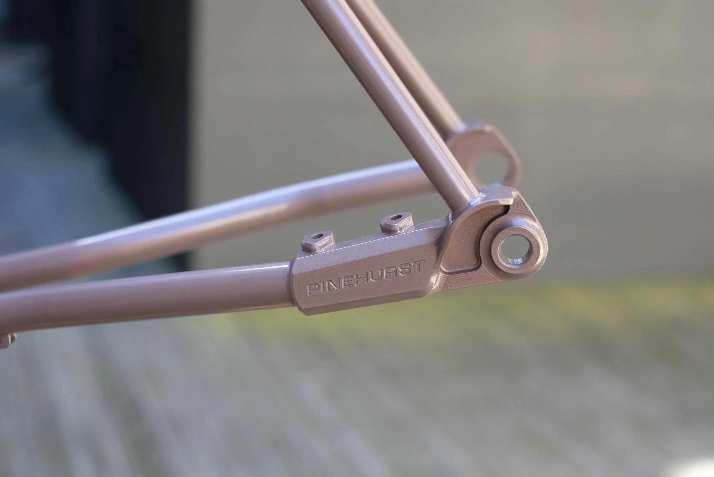 Close-up of a metallic bicycle frame with the brand name ''PINEHURST'' engraved on it, on a flat surface.