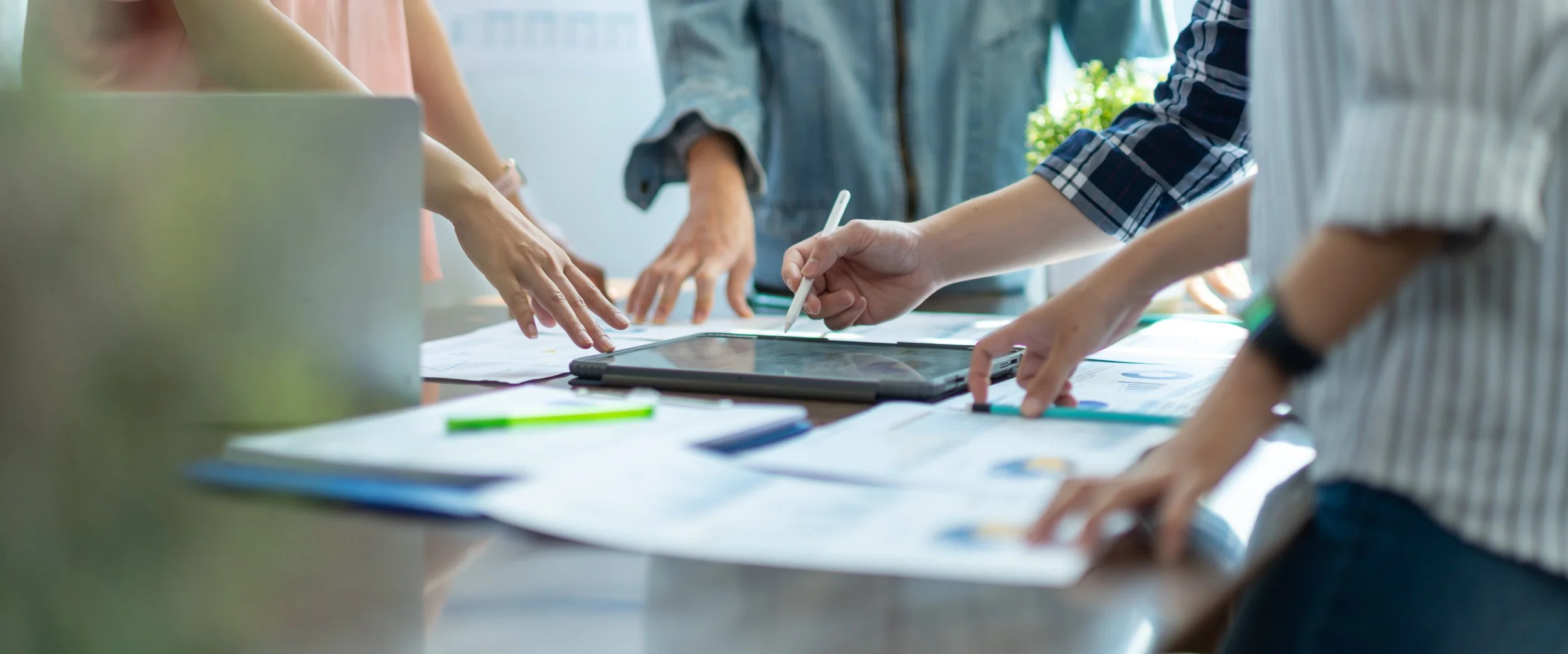 People working together around a table with documents, a tablet, and pens.