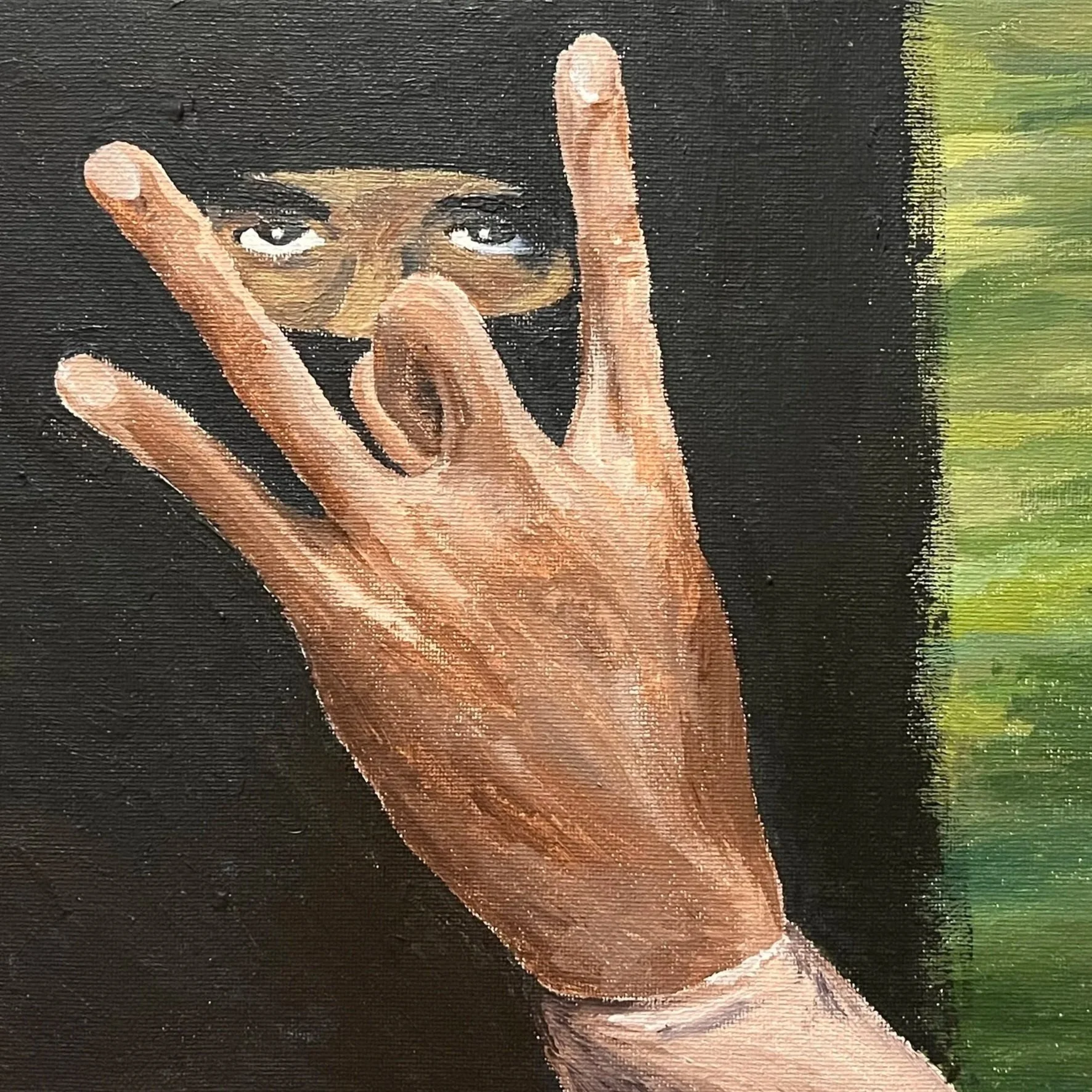 A person with black hair and makeup covering the lower half of their face, holding their hand up in front of their face with fingers splayed, with green trees in the background.