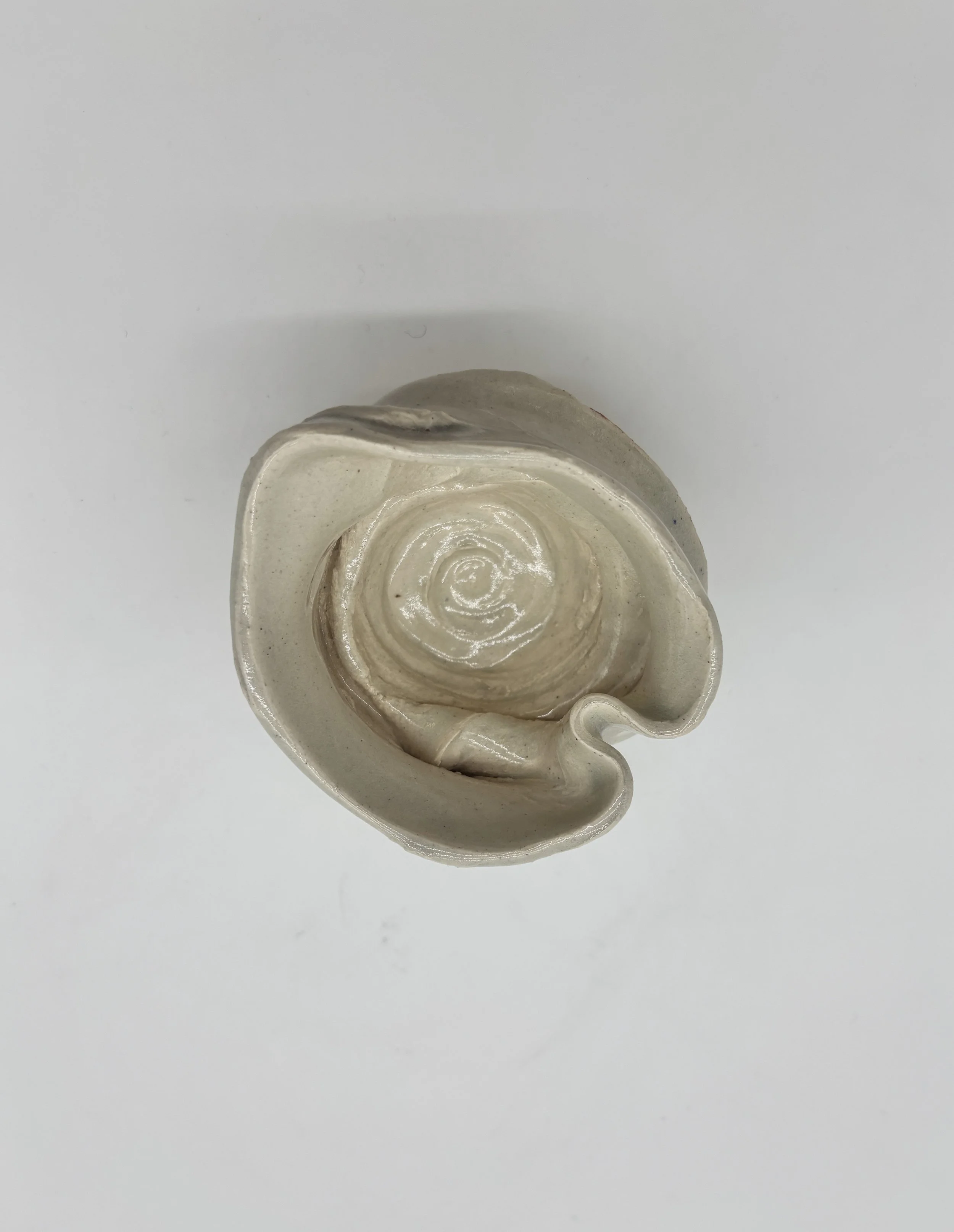 A ceramic sculpture shaped like a human ear, viewed from above on a white background.