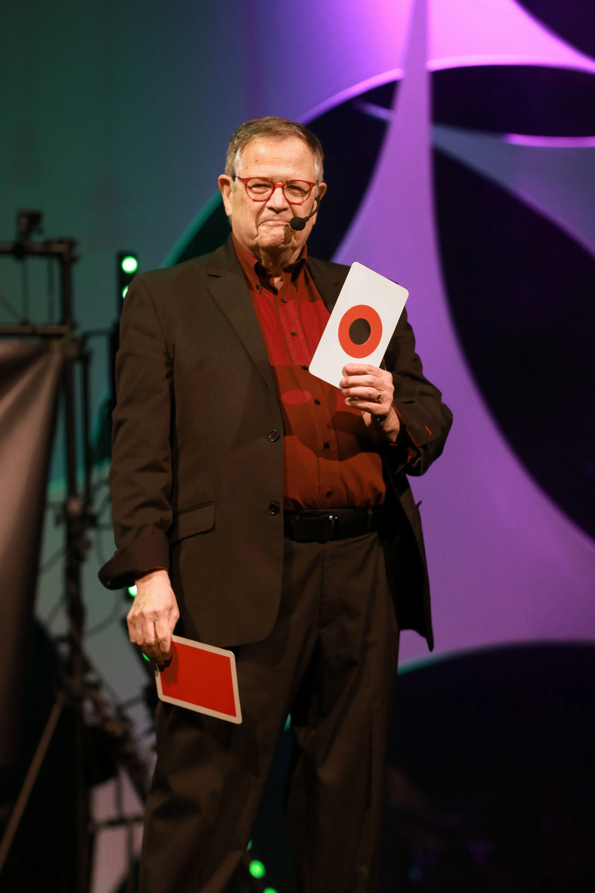 Pete Waltersheid magician in black jacket and red shirt holding cards