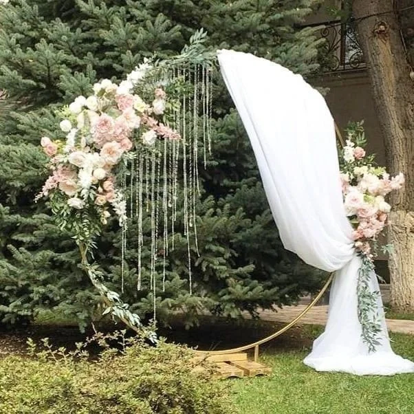 Bride and groom kissing under a draped wooden arch on a beach with the ocean in the background.  Beach ceremonies by interior scapes wedding officiant ventura county
