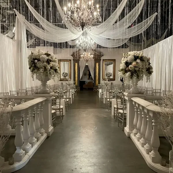 Elegant banquet hall decorated with white drapery, chandeliers, and large floral centerpieces for a wedding or formal event. venues near me-local venues-interior scapes events by julie jenkins