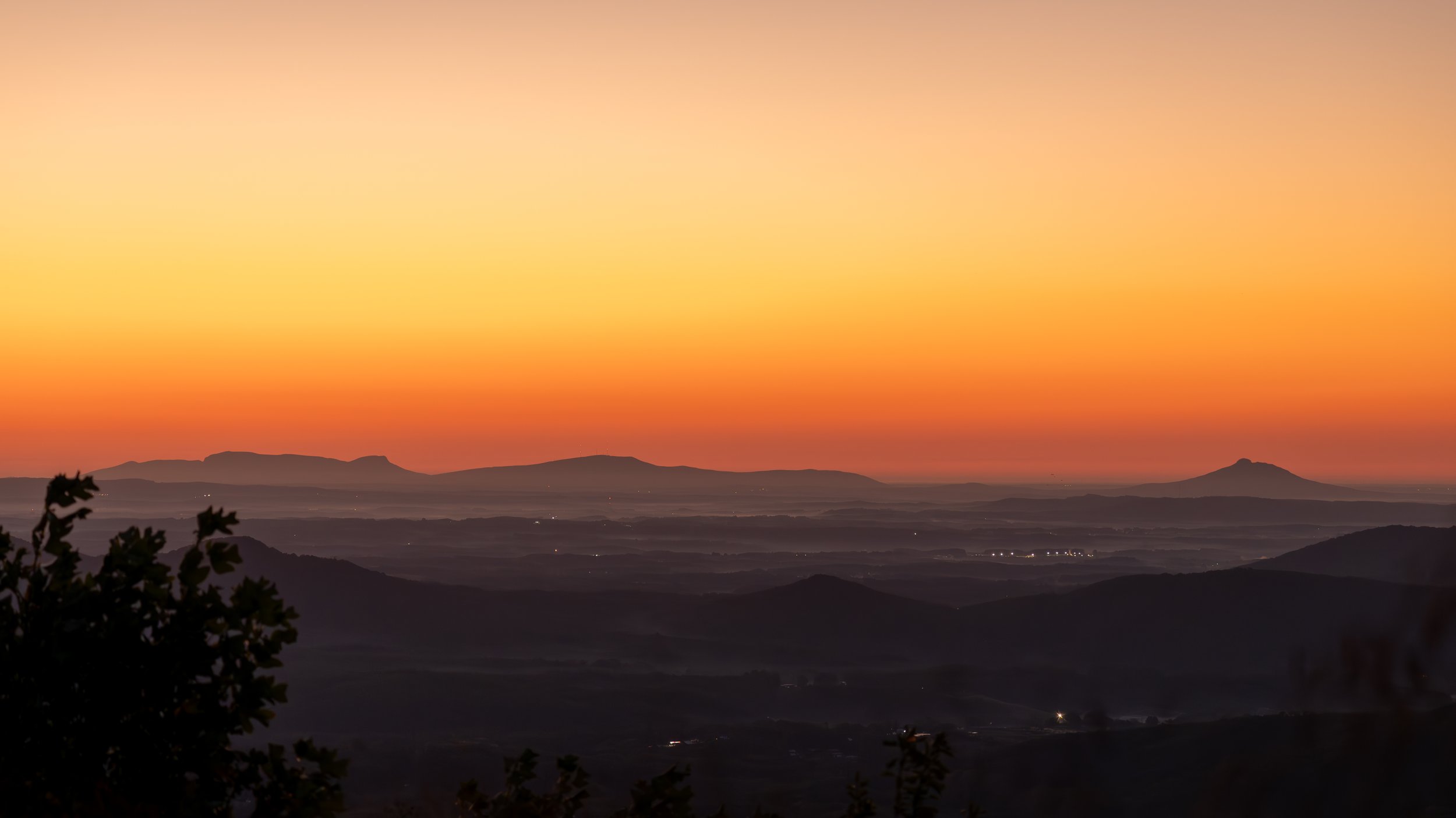 Sunrise over Hanging Rock and Pilot Mt. State parks with an orange gradient sky taken from the Blue Ridge Parkway.