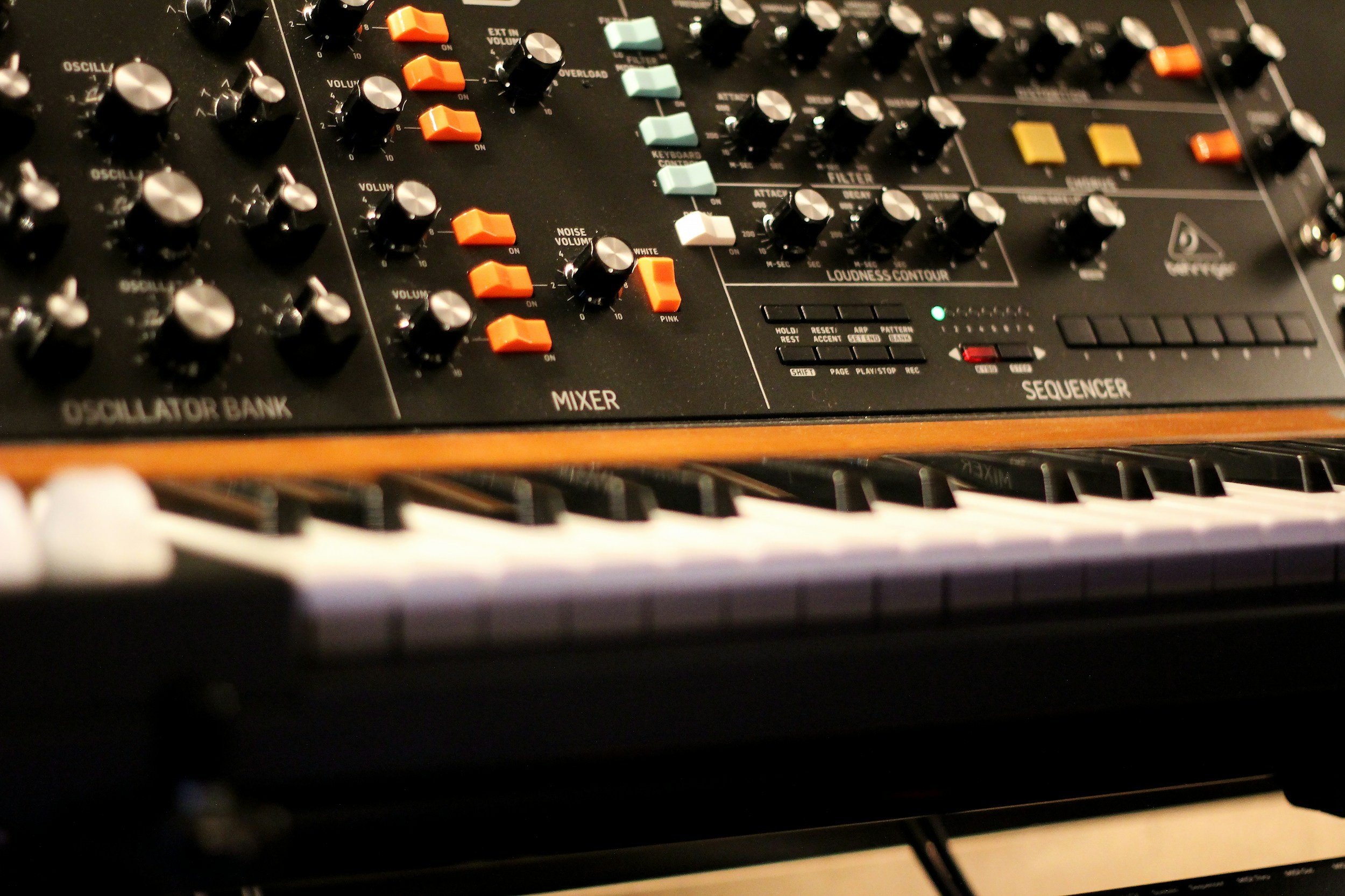 Table de mixage de musique avec plusieurs boutons, manettes et touches, comprenant des sections pour oscillateurs, mixage, séquencer et contrôle du volume.