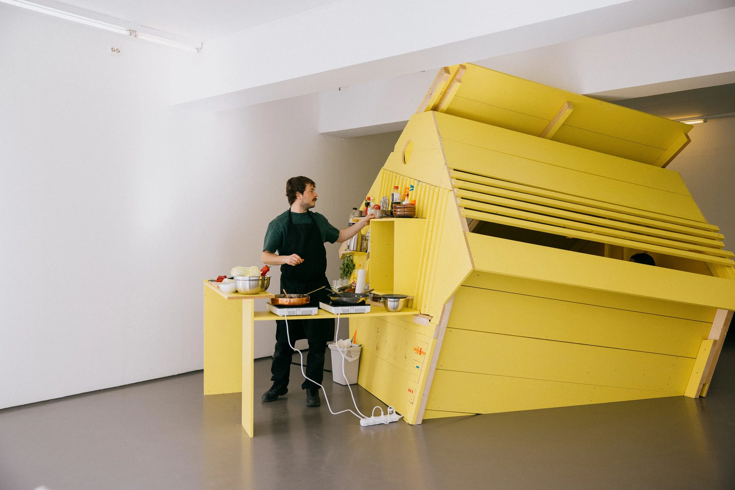 Fergus Tibbs artist preparing food for visitors to the gallery. The installation functioned as a cafe and gathering place.