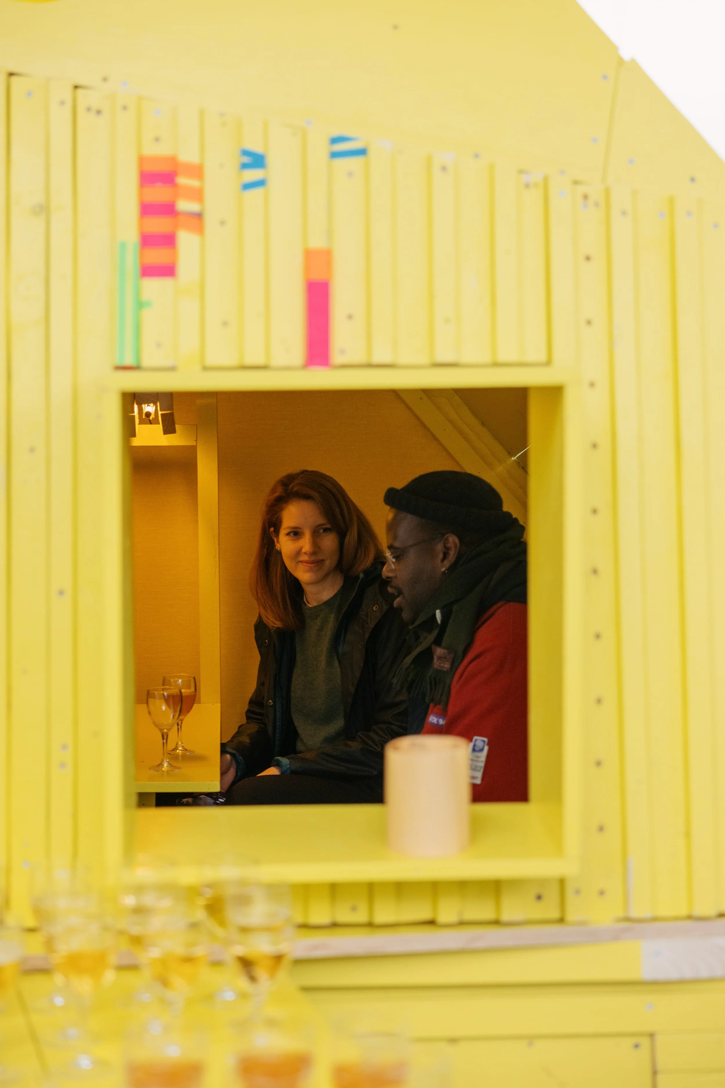 Visitors enjoying a conversation and drink inside Fergus Tibbs art installation titled hosting infrastructure