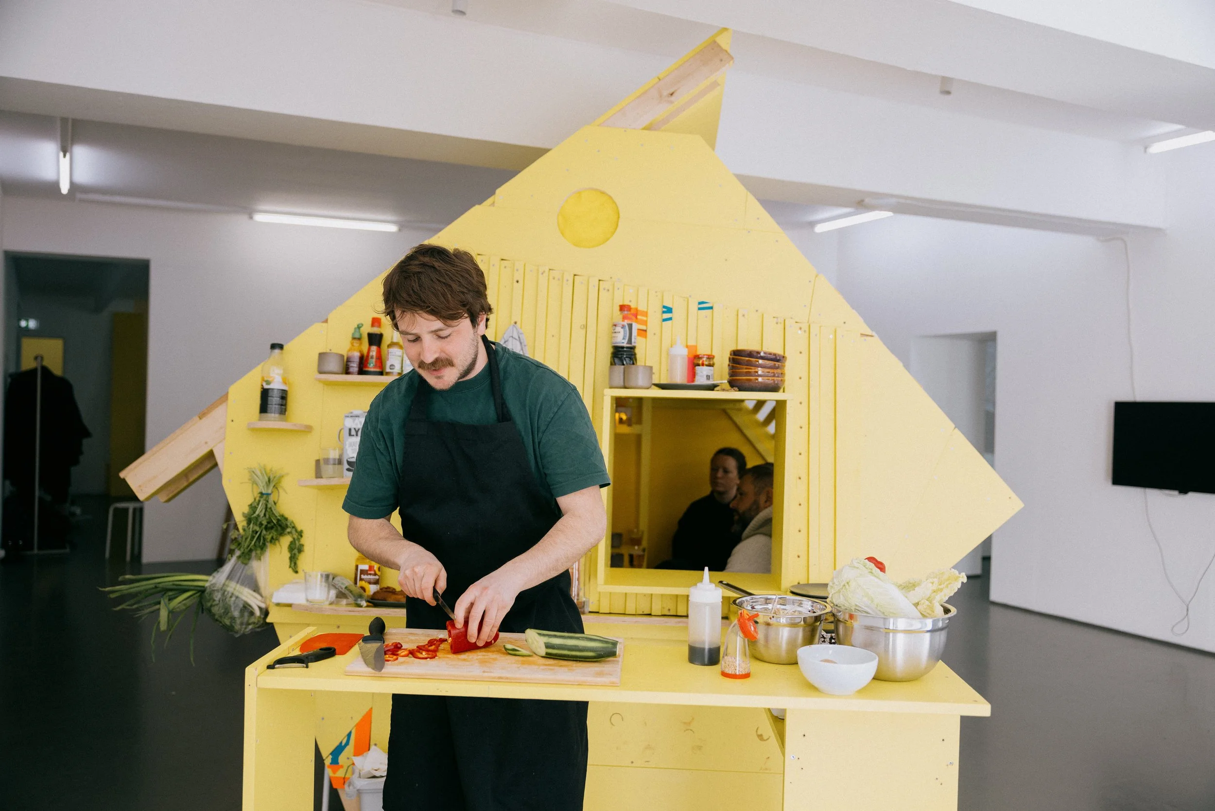 Fergus Tibbs artist cooking for visitors to the gallery. Visitors could sit and eat inside the art installation