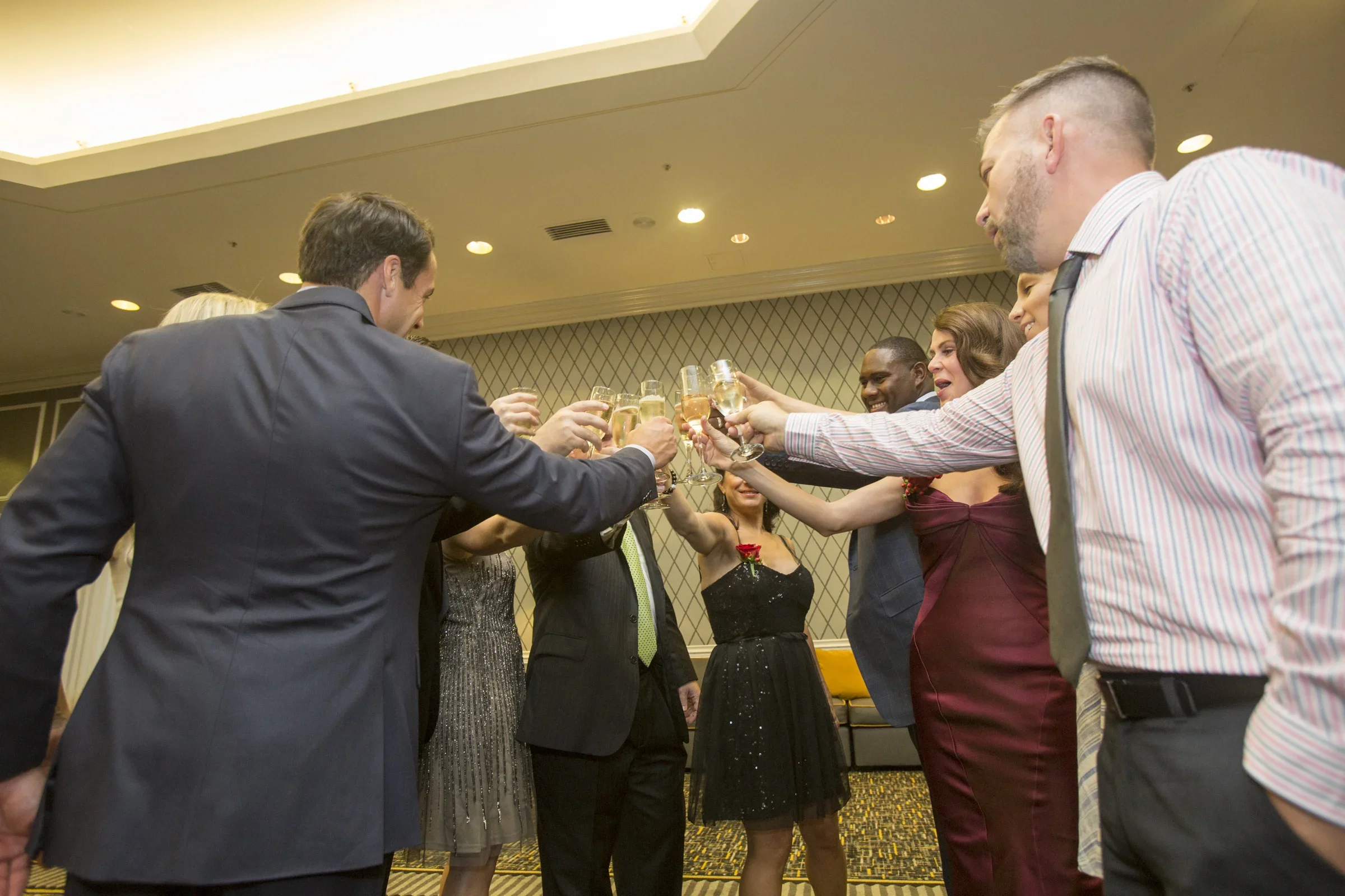 A group of people in formal attire raising glasses for a toast at a celebration or event in a banquet hall.