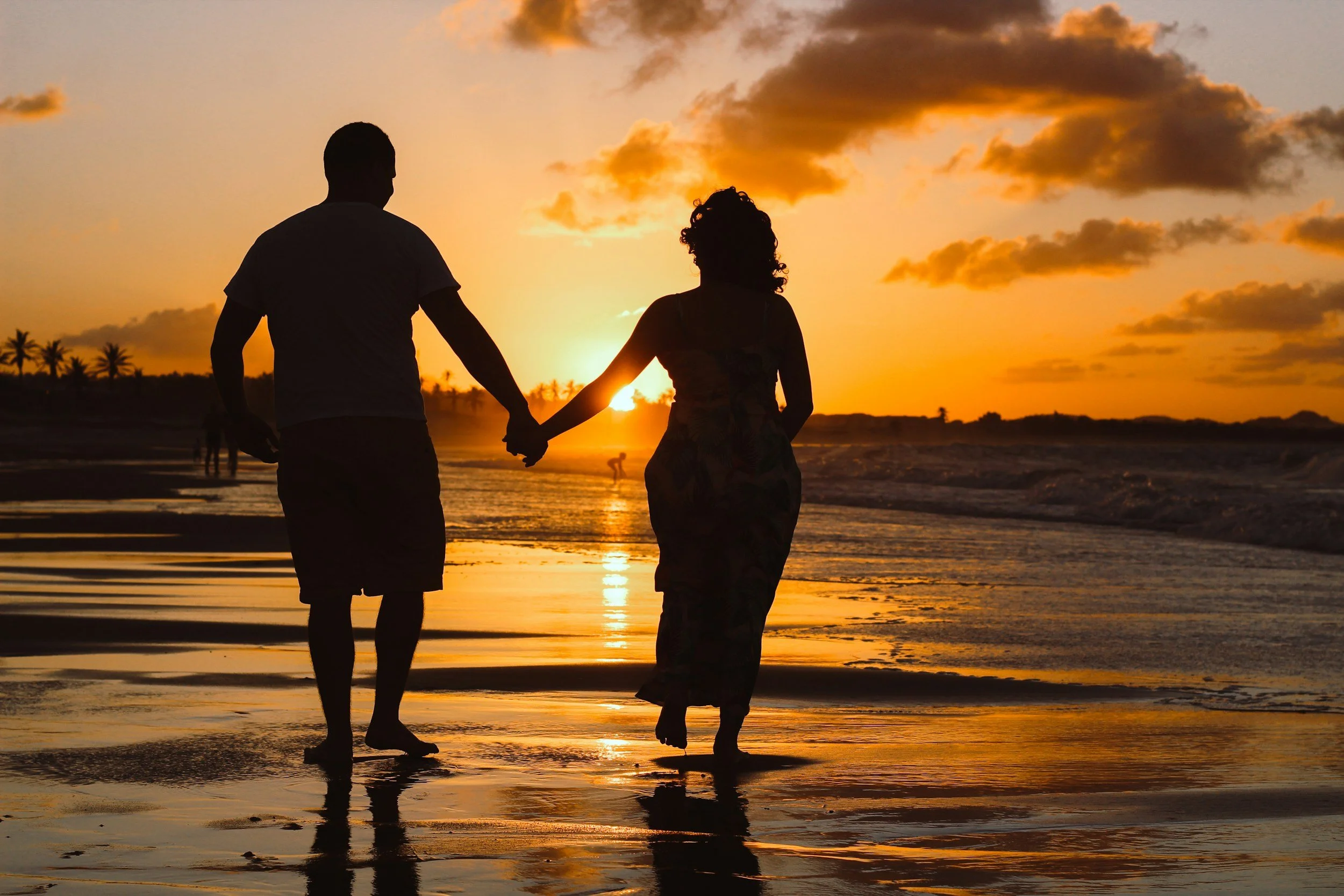 Couples holding hands walking on the beach at sunset